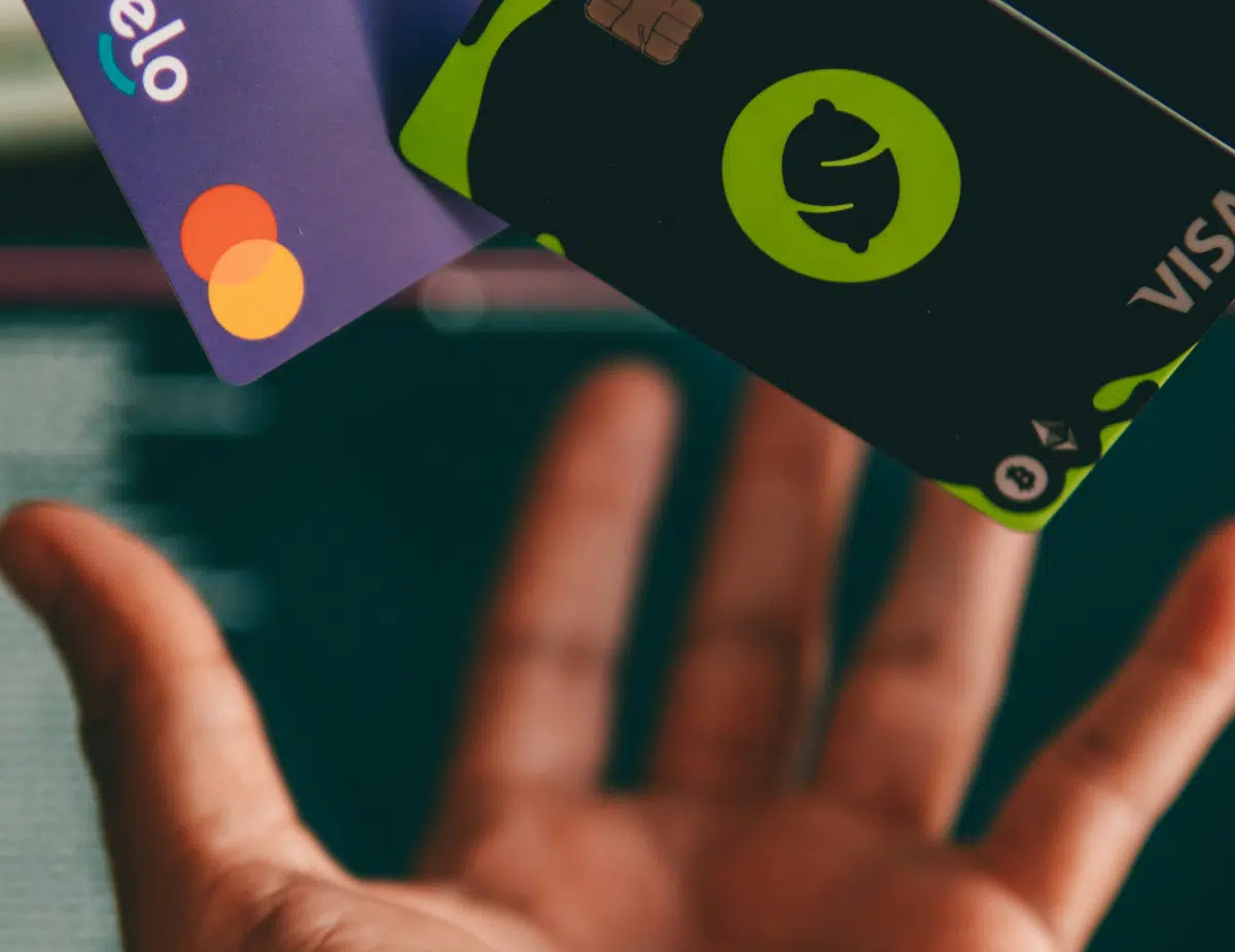 a hand holding a credit card in front of a computer