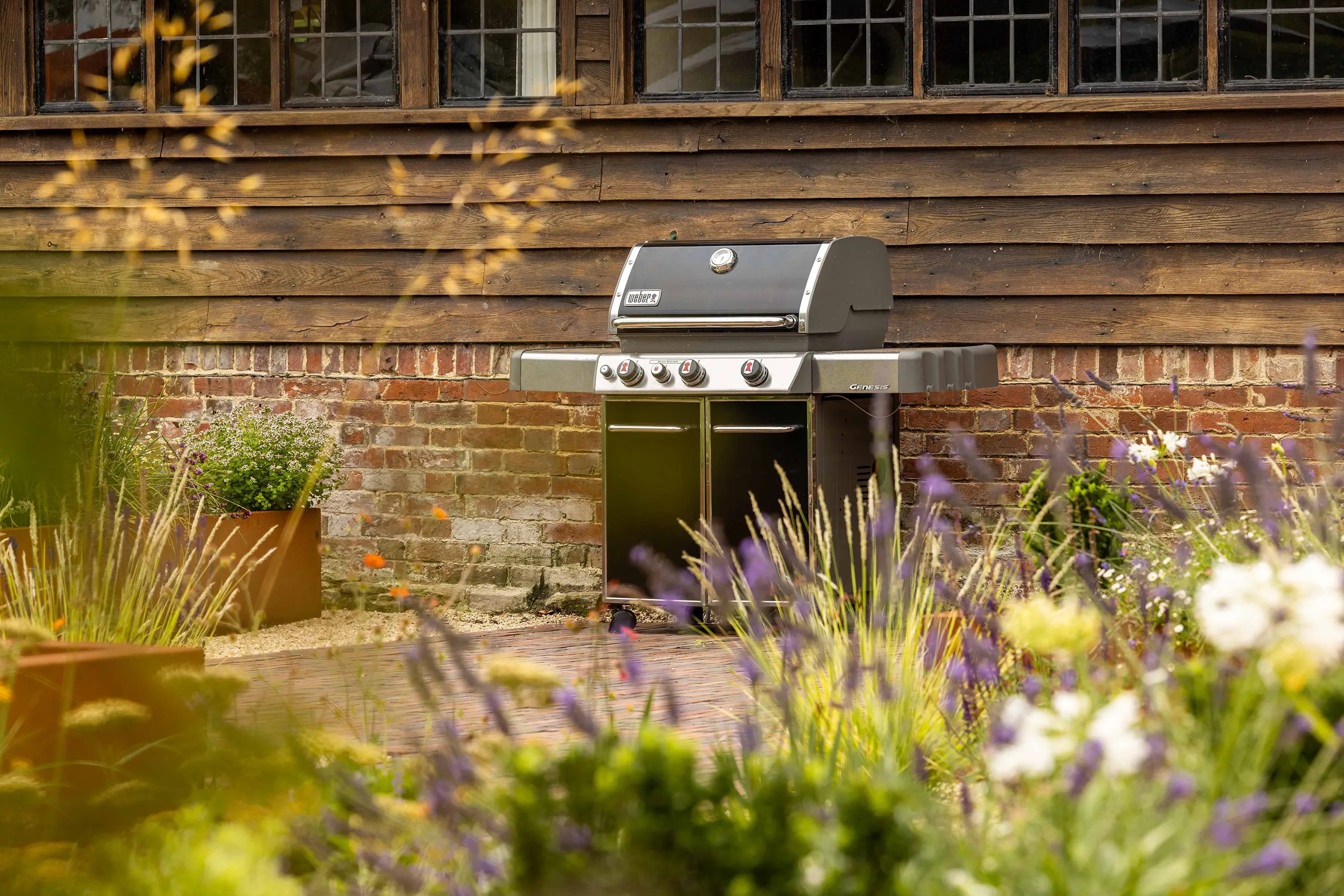 A serene garden scene featuring flowers and greenery in front of a wooden structure with stairs.