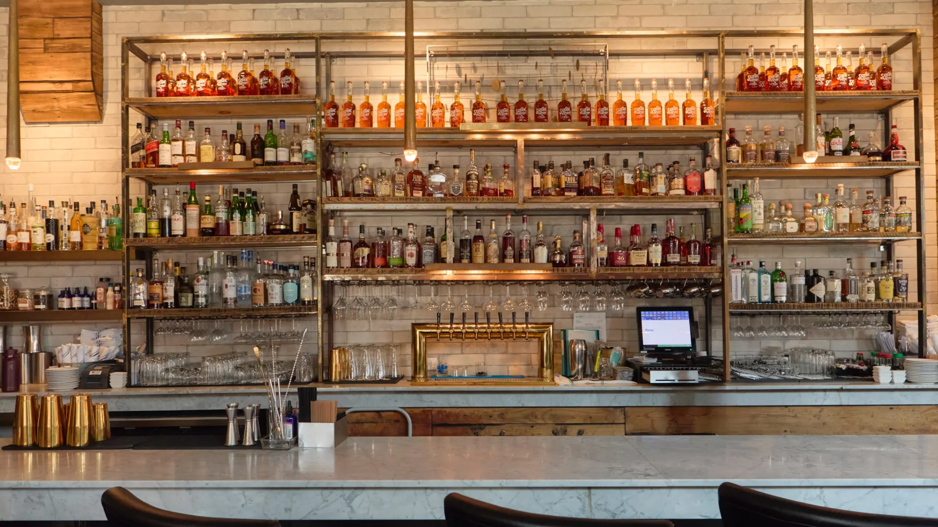 Long bar with white tile and stocked shelves at South Village Grille