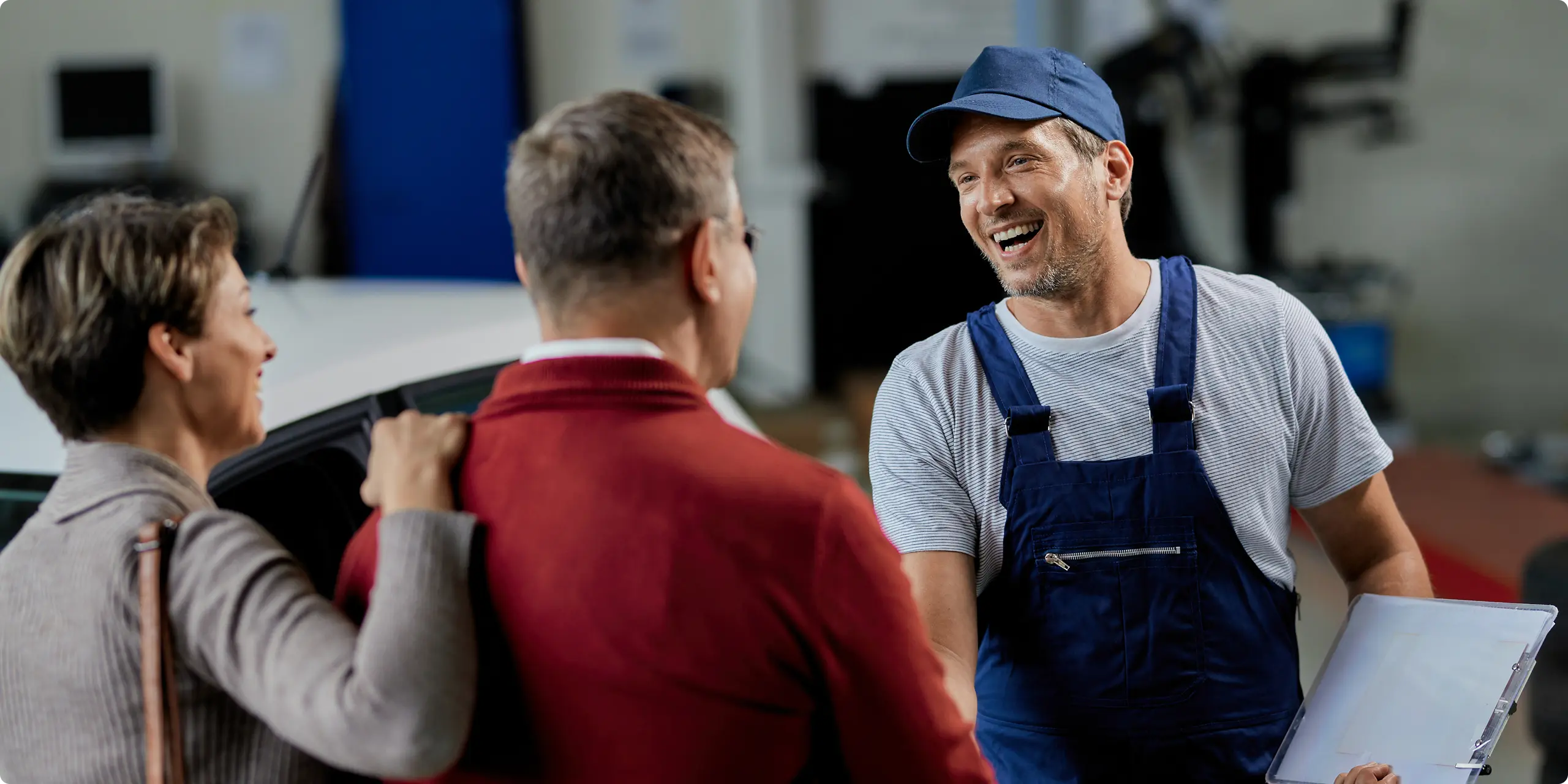 Smiling Pipewise plumber greeting a couple of homeowners