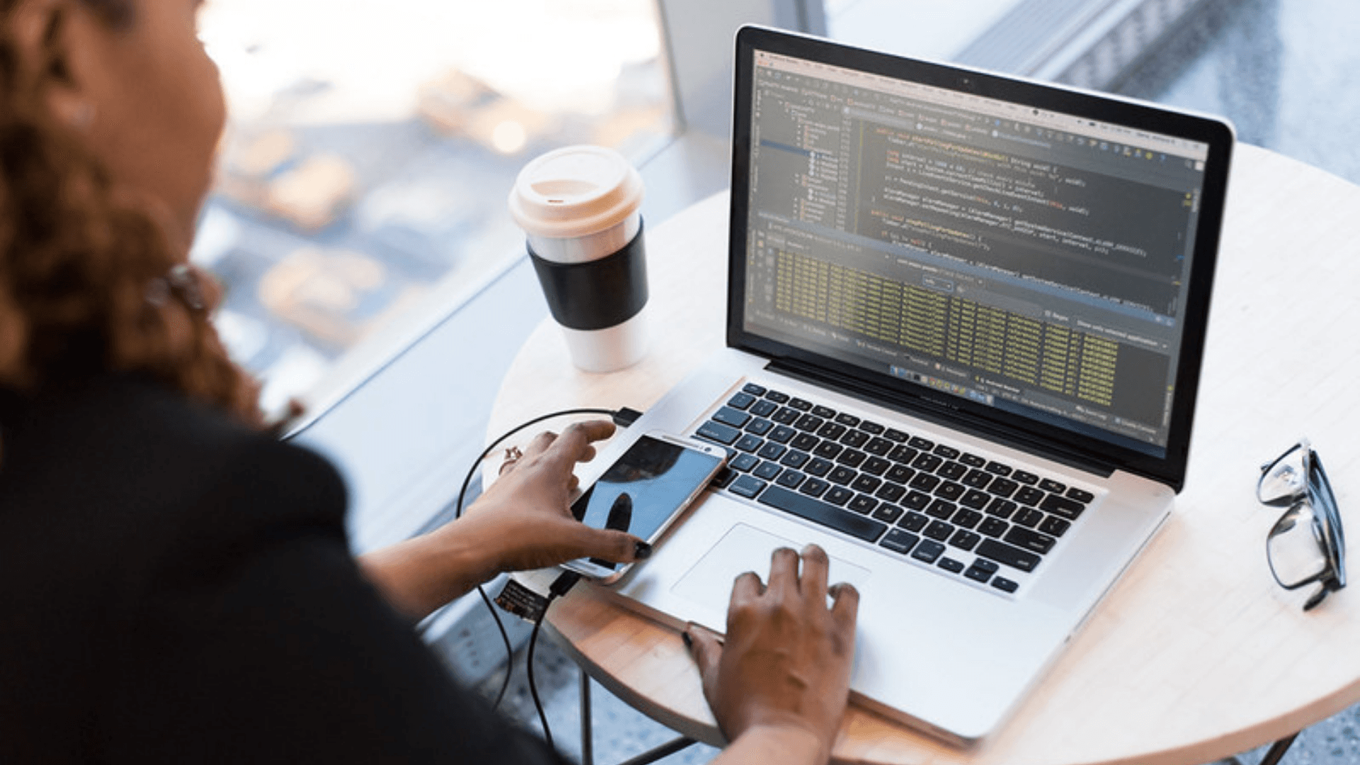 A woman working on her latop at a small table