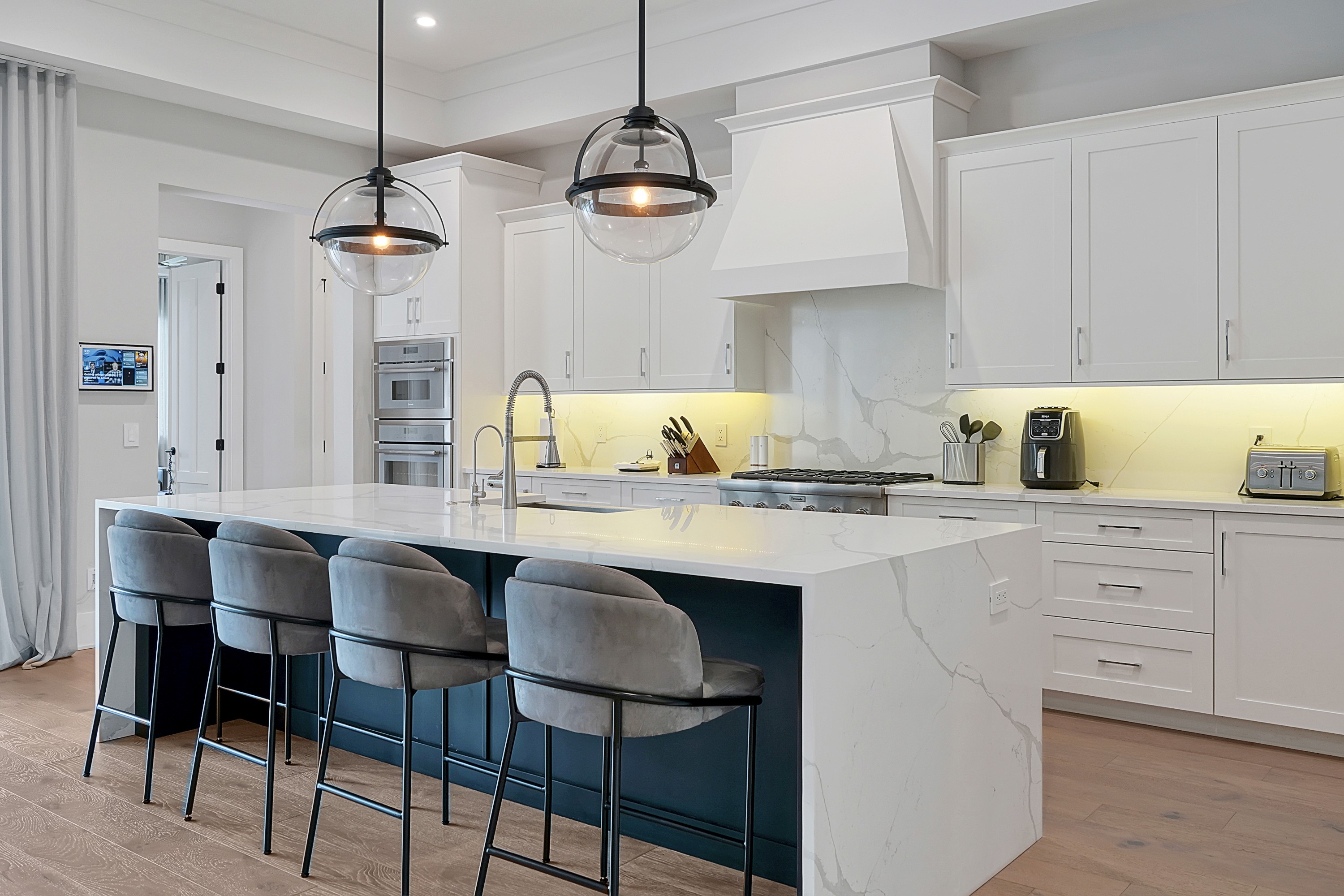 Bright white kitchen with large island and pendant lights.