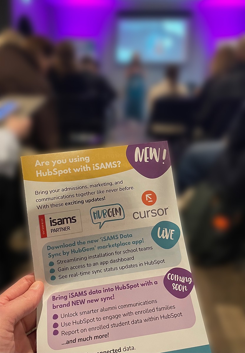 A HubGem flyer held up at HubGem LIVE! Balham, promoting the new iSAMS Data Sync by HubGem marketplace app and upcoming HubSpot with iSAMS integration features