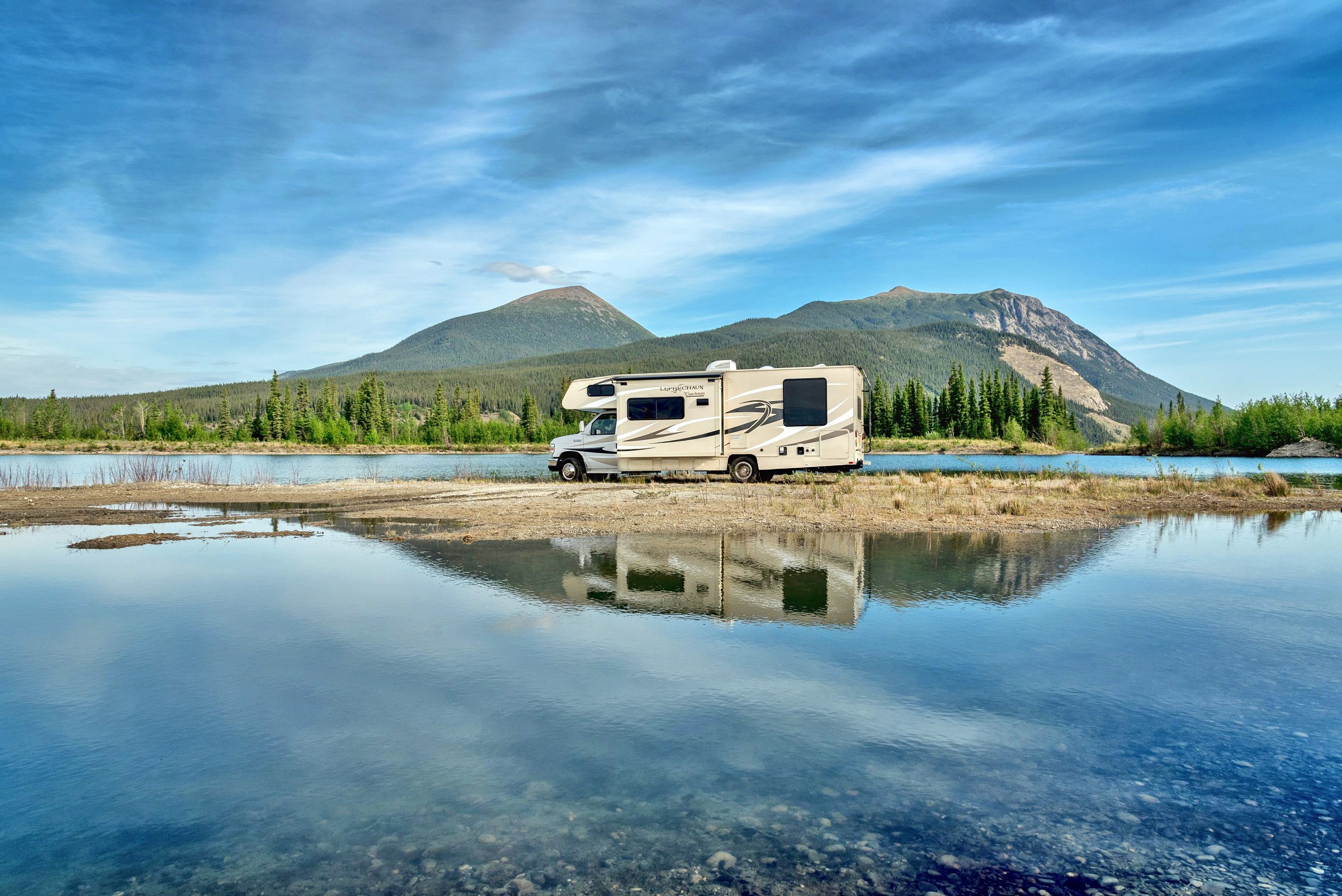 RV by lake with mountains and reflection