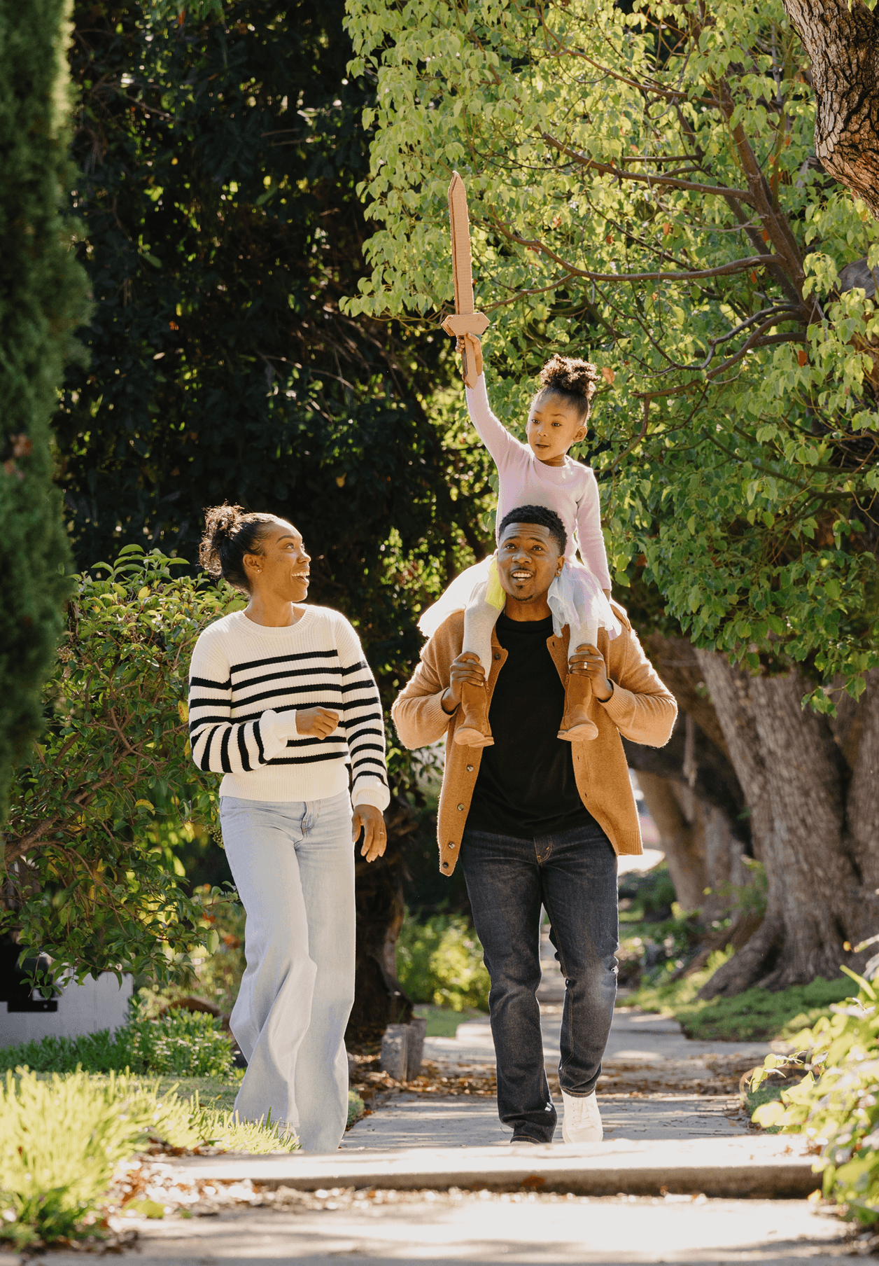 A family walking together on a sunny sidewalk.