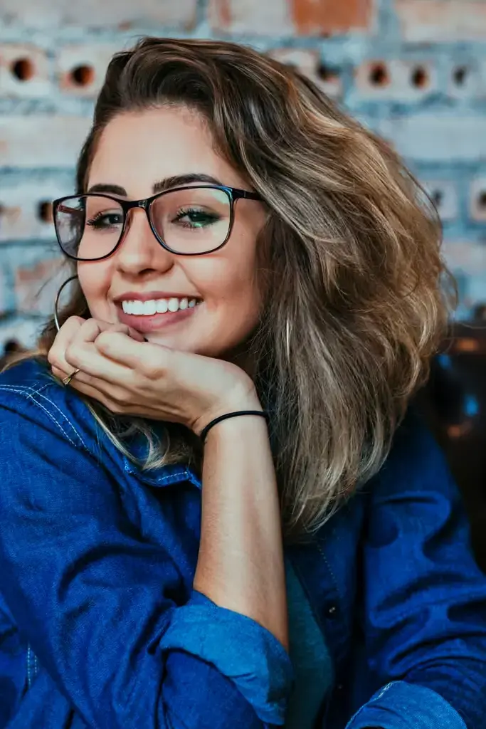 Mulher sorrindo e usando óculos, representando a análise de perfil e comportamento do público para campanhas de marketing mais assertivas em eventos.