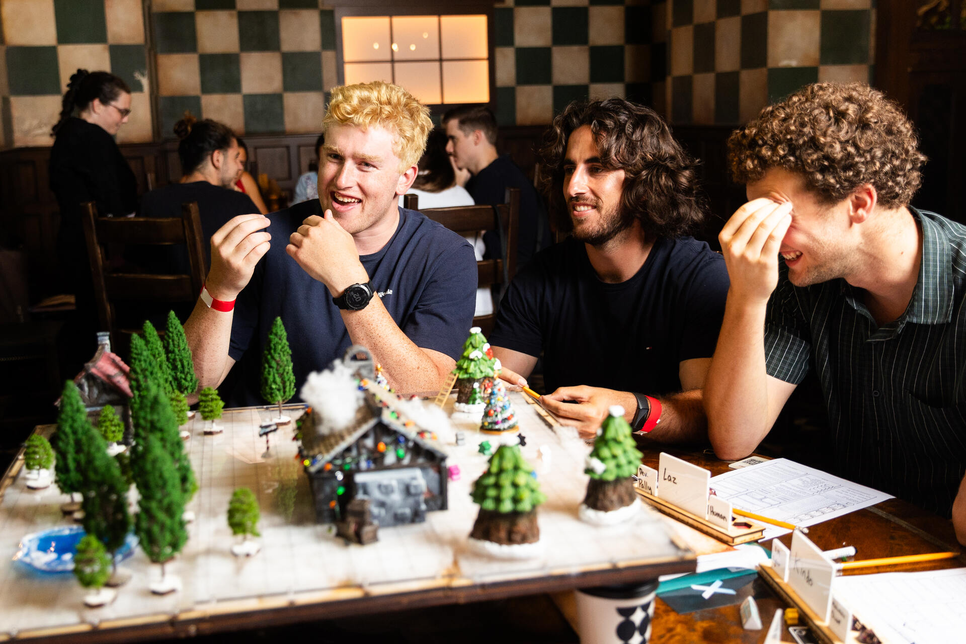 three guys playing d&d and laughing around a table set up with map pieces and sheets