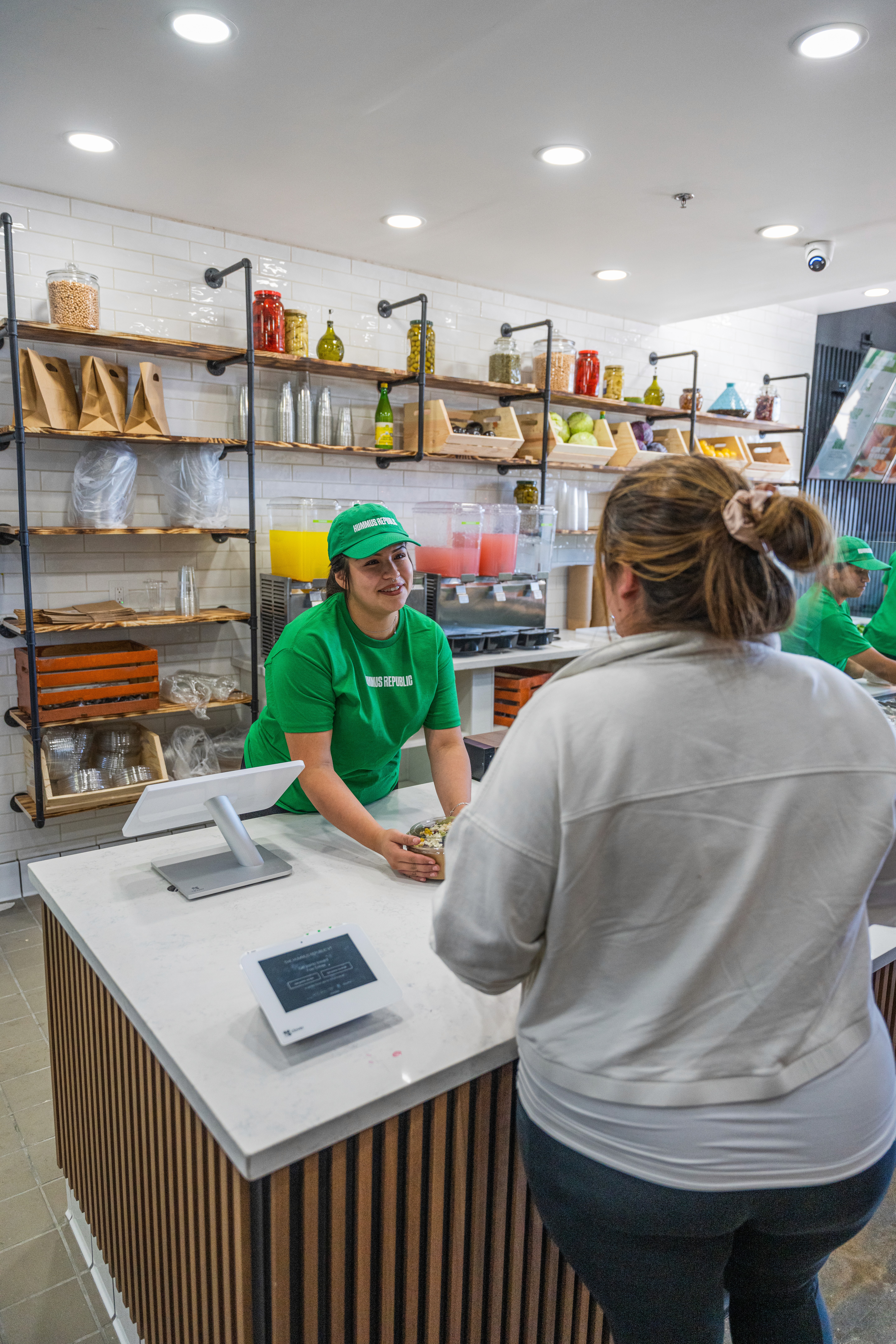 women behind the point of sale handing a order to a customer