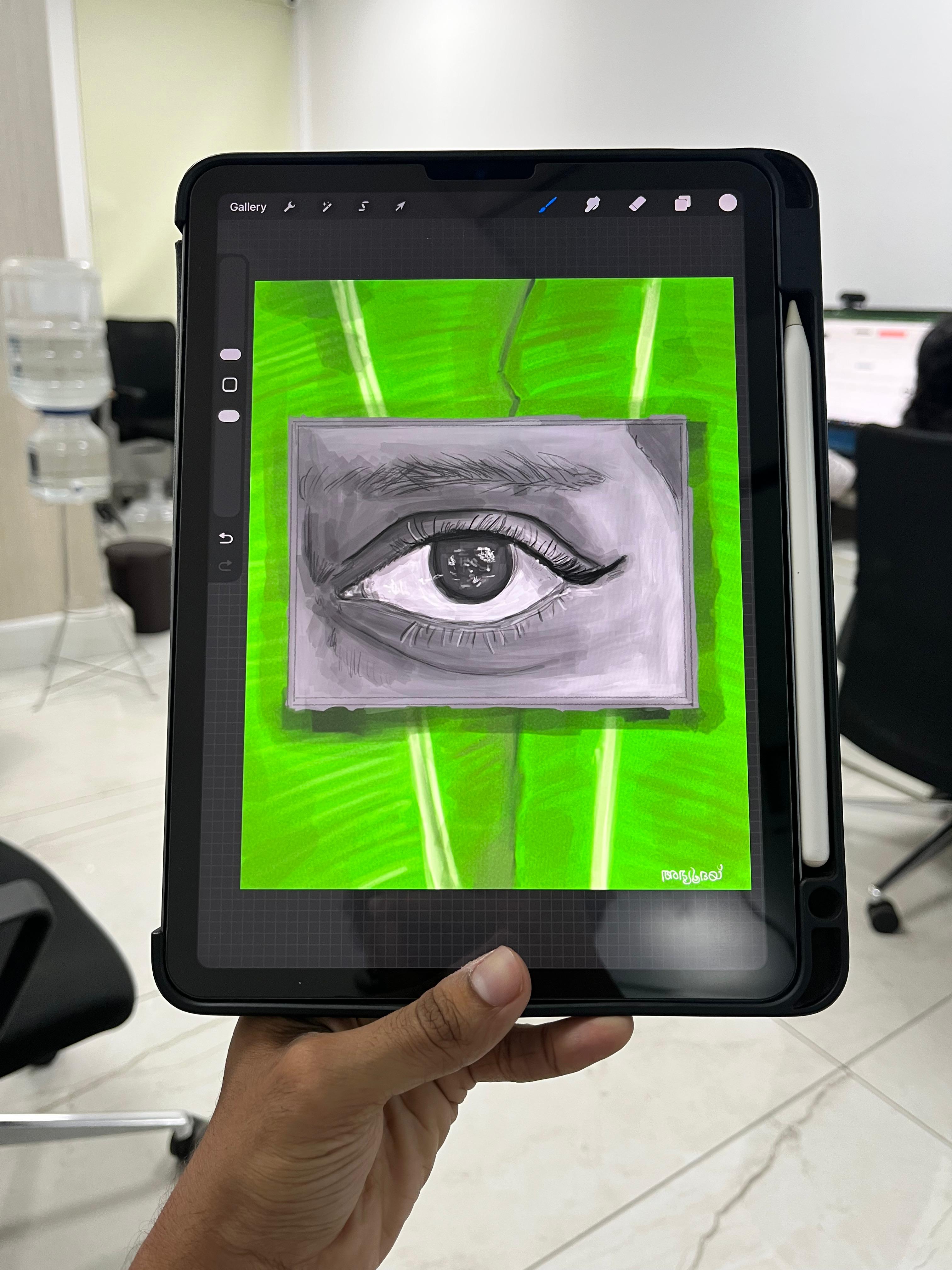 A hand holding a tablet showing a pencil drawing of an eye