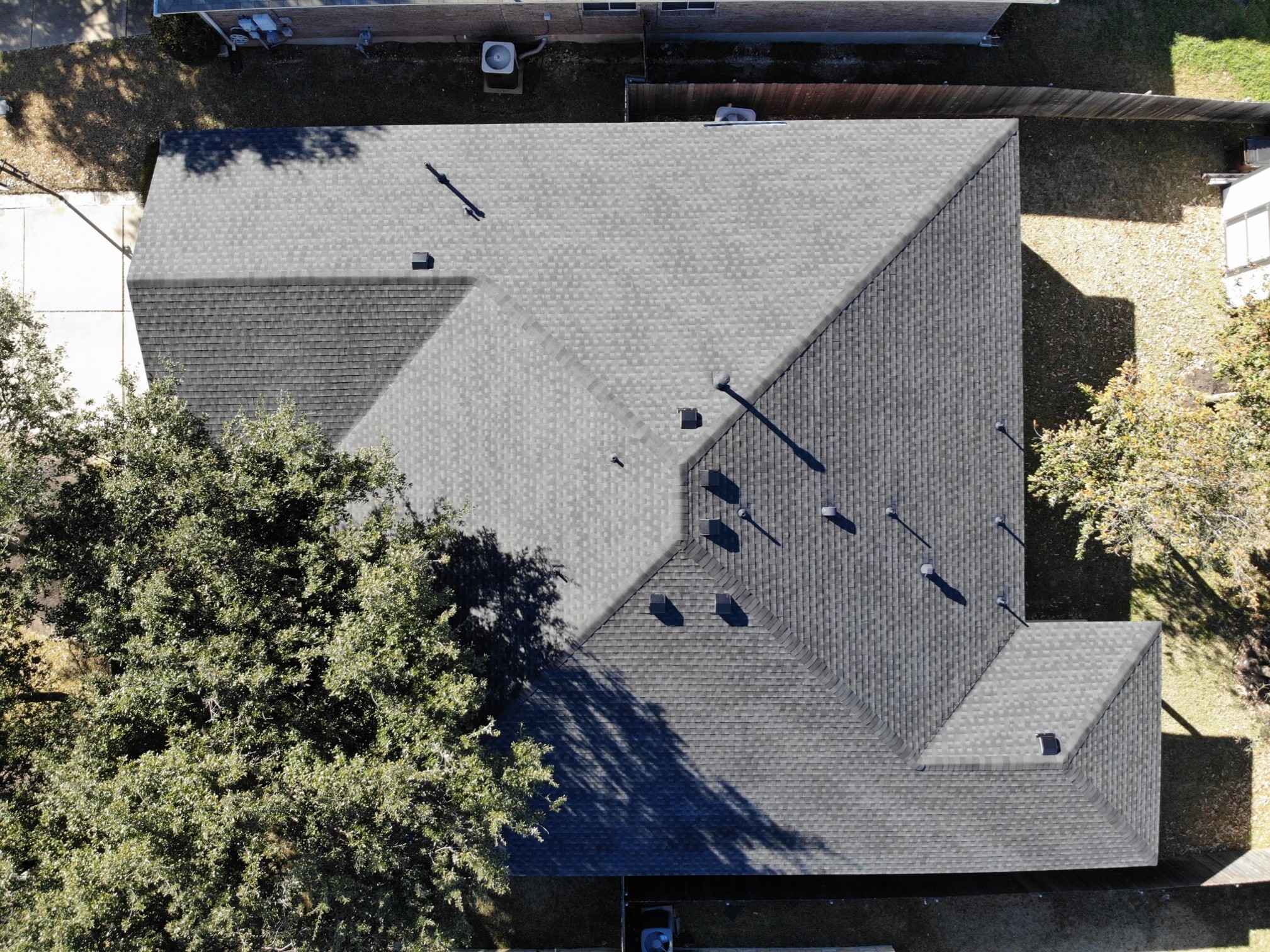 A one-story house with a weathered wood-colored hip roof, featuring GAF HDZ Timberline architectural shingles. The roof has a smooth, sloping design with the dimensional shingles adding depth and texture.