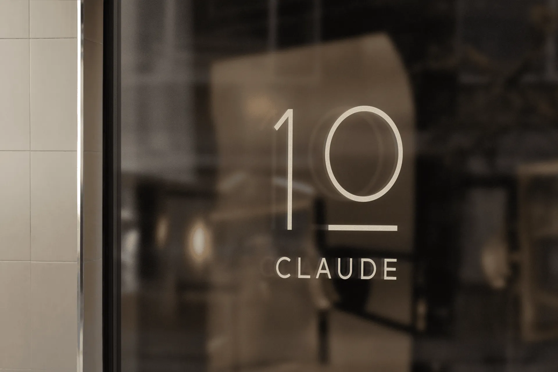 Glazen deur met het logo ‘10 Claude’ bij de ingang