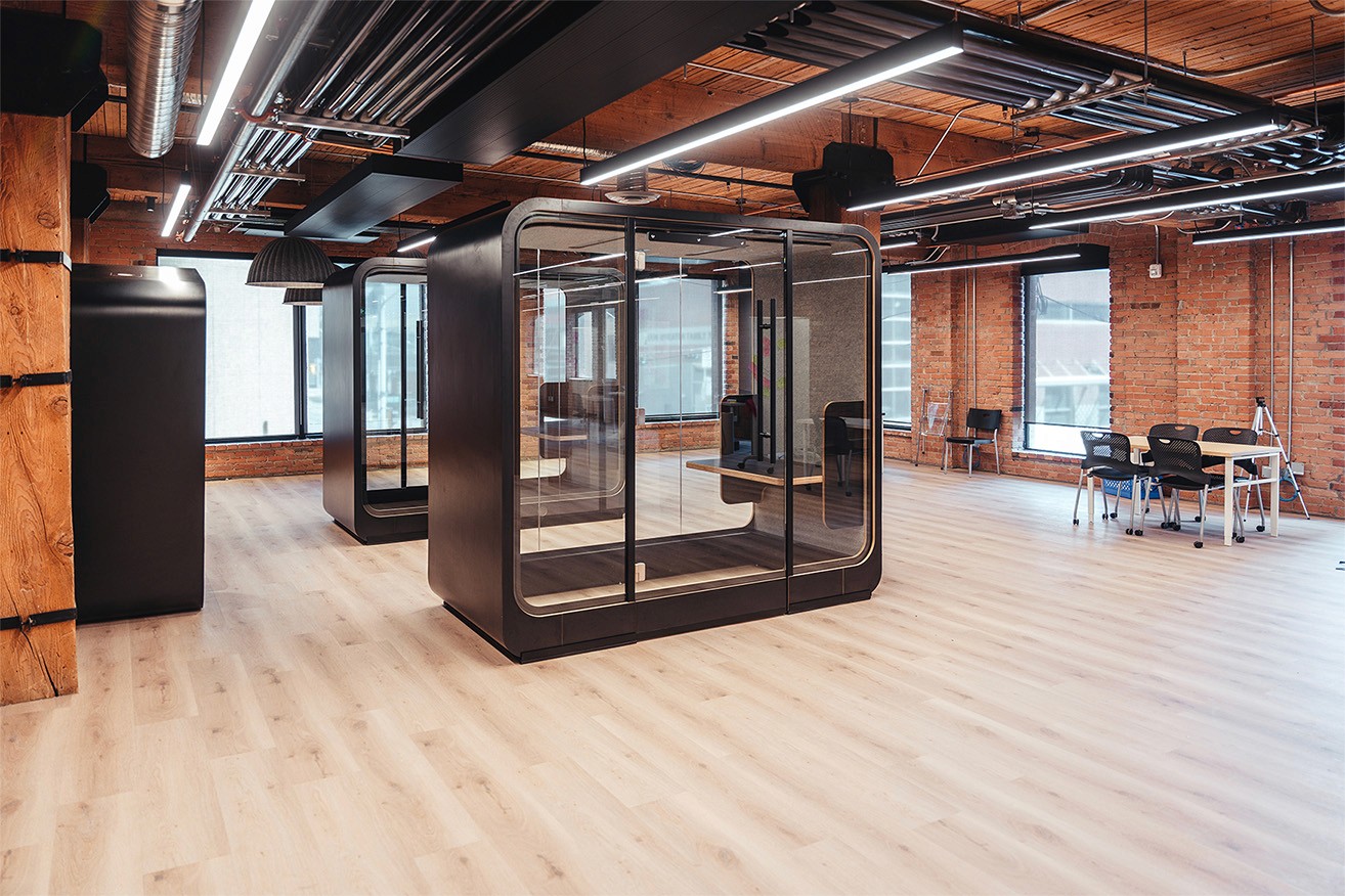 a large office pod in a exposed brick room with large wooden beams on the cieling