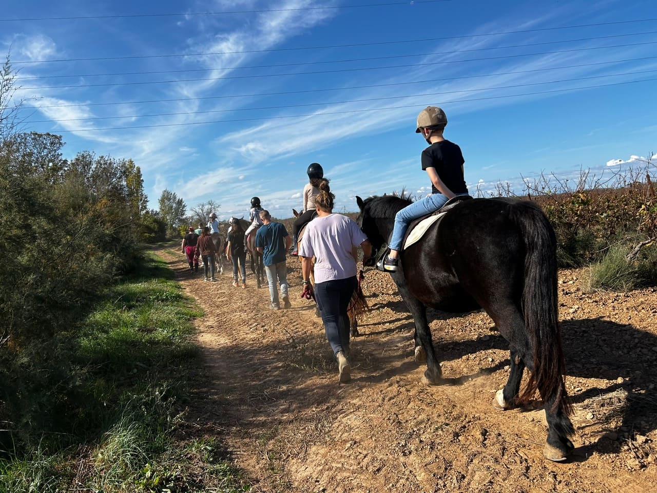 File indienne de cavaliers souriants en promenade équestre en pleine nature près de Bessan