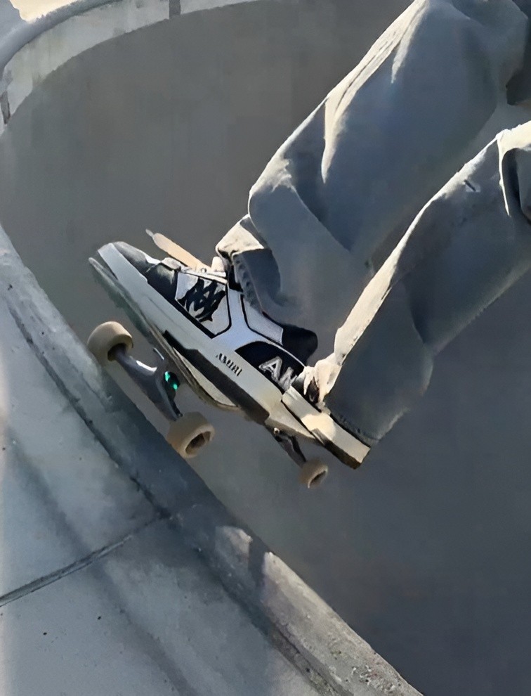 A close-up of a skater wearing Amiri sneakers while dropping into a concrete wall