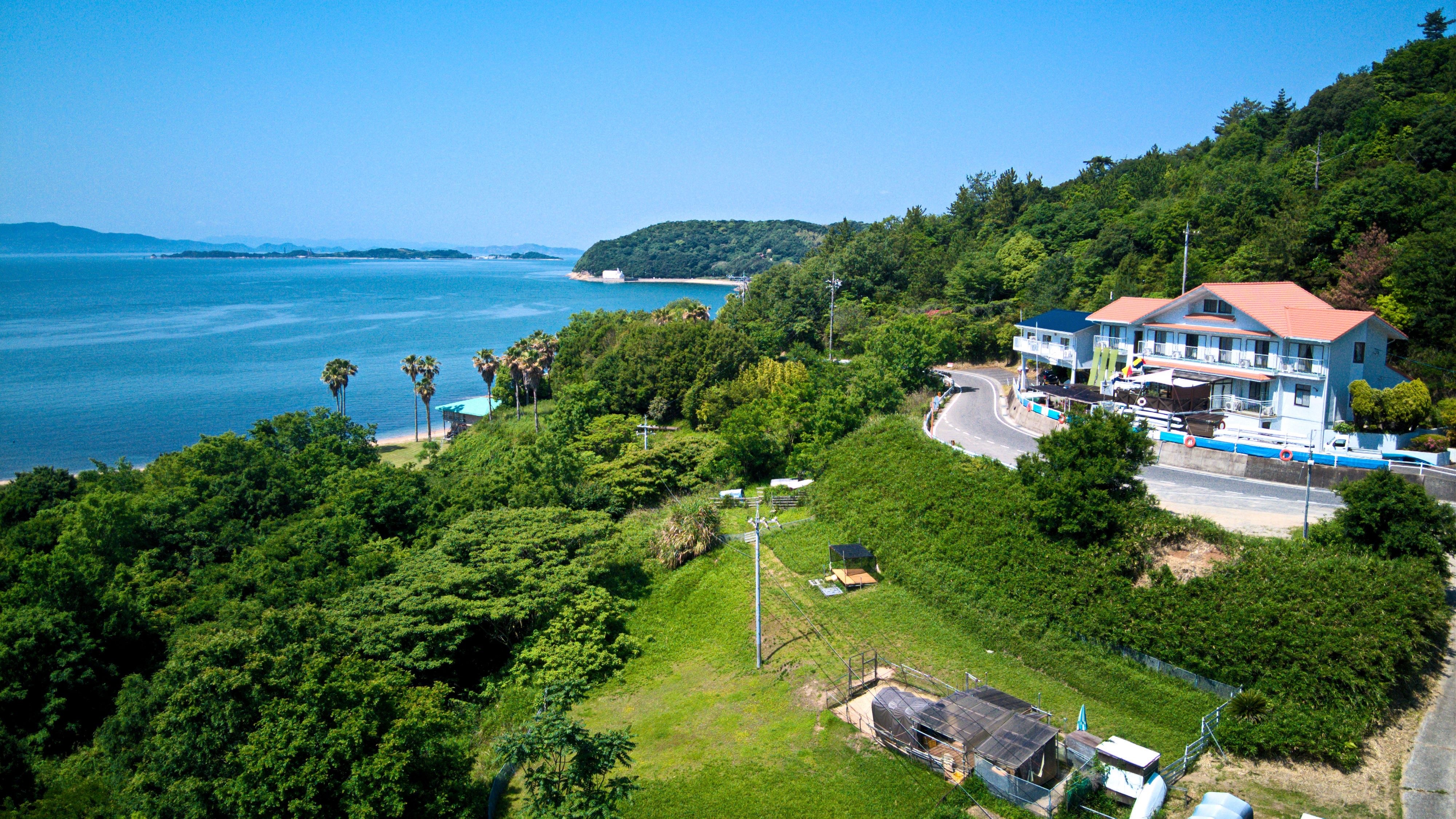 Aerial view of the hotel and the seaside on a slopped green hillside