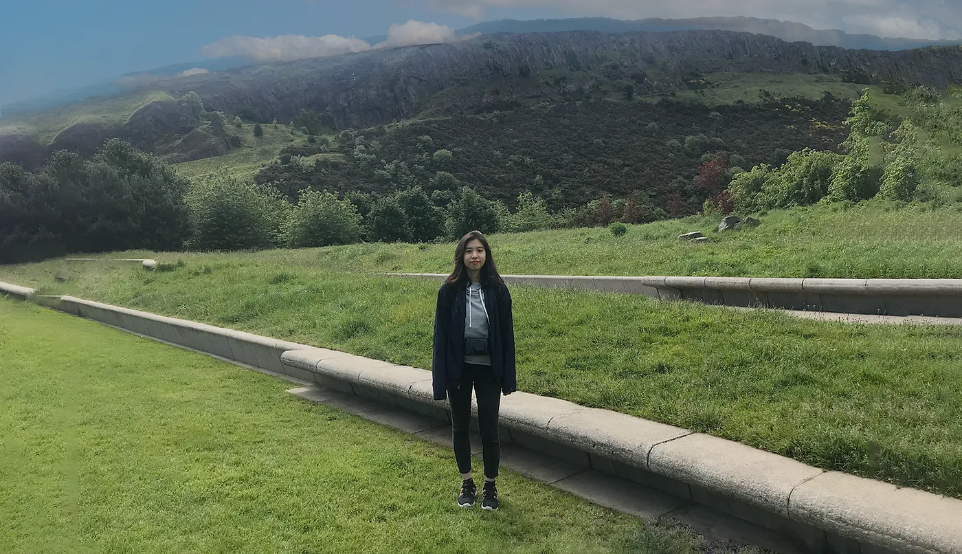 Kay standing in a field with mountains in the background