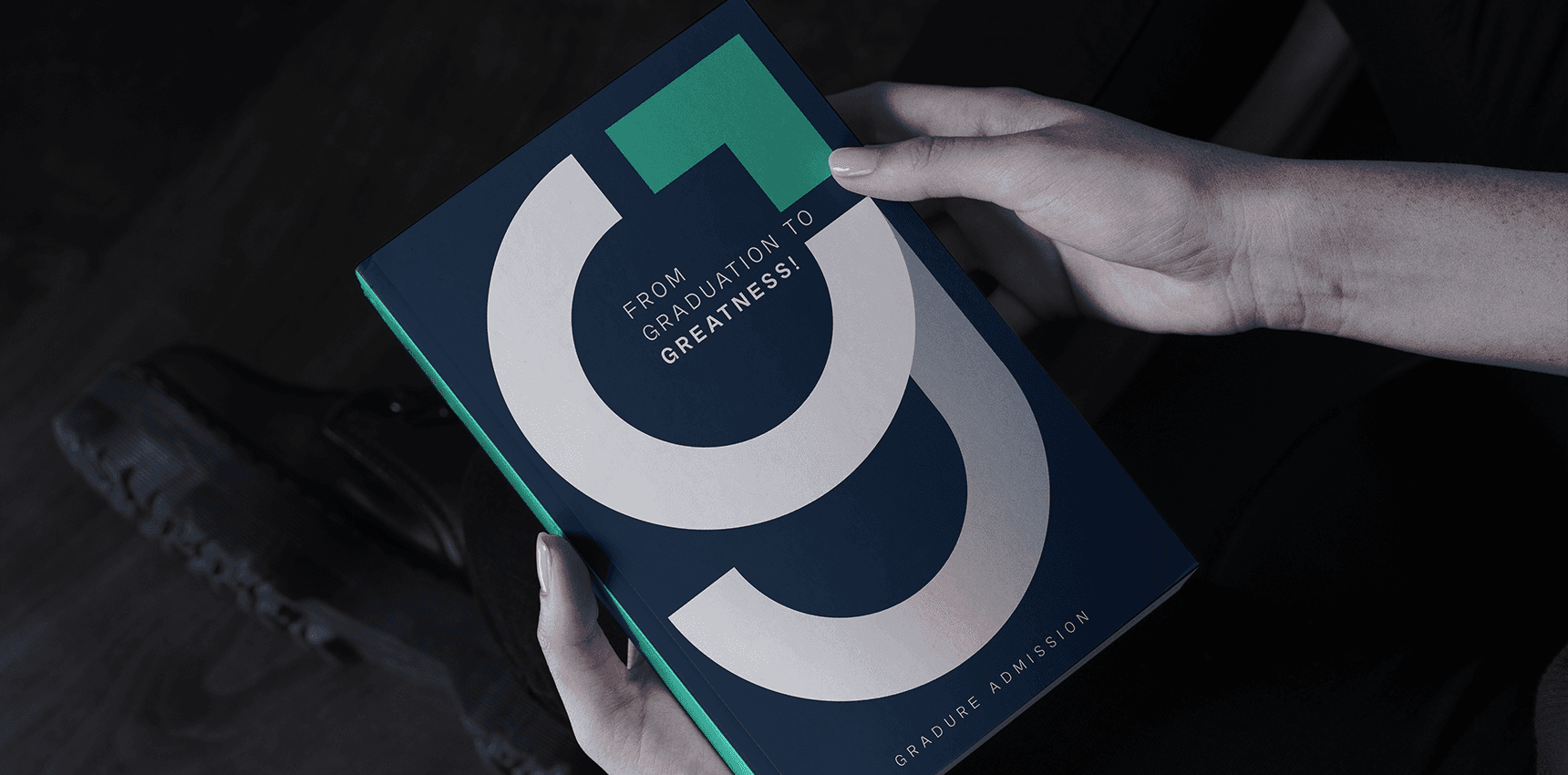 Person holding a Gradure Admission booklet with the bold ‘G’ logo and the tagline ‘From Graduation to Greatness’ on a navy blue cover.
