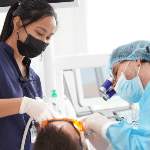 A dental assistant is treating a patient's teeth while a dentist oversees the dental crowning at Invisalign Center, Dubai.