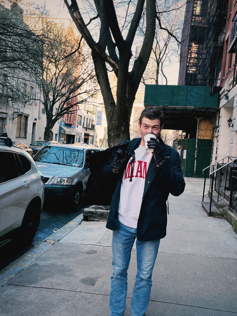 Will walking down a city street with coffee