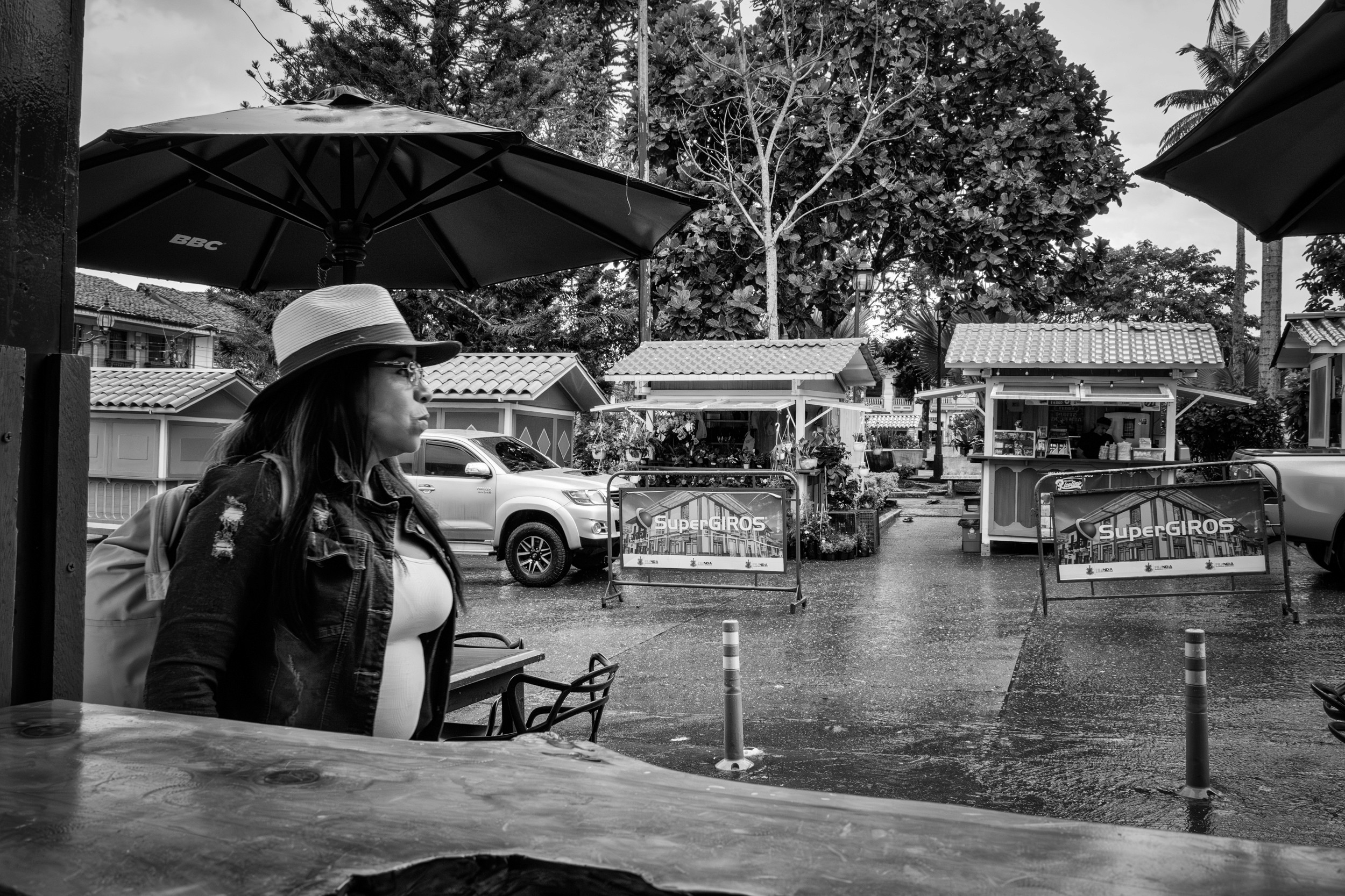 Rainy street scene with people passing by a bar window.