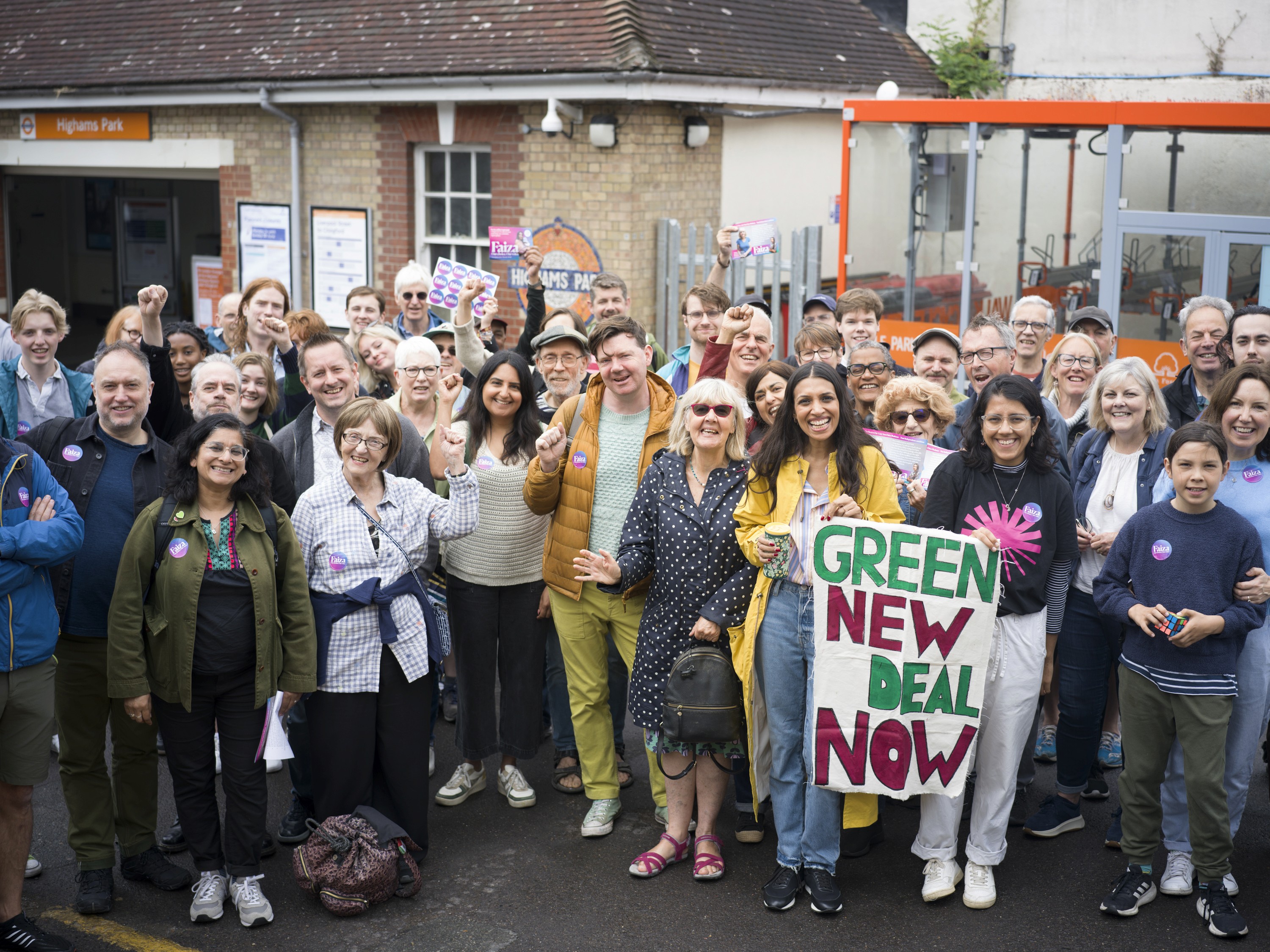 Group of diverse people at a community event outside a train station.