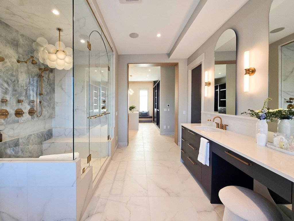 Image of Luxurious primary ensuite bathroom with marble tiles, gold fixtures, and modern design by KHD Homes.
