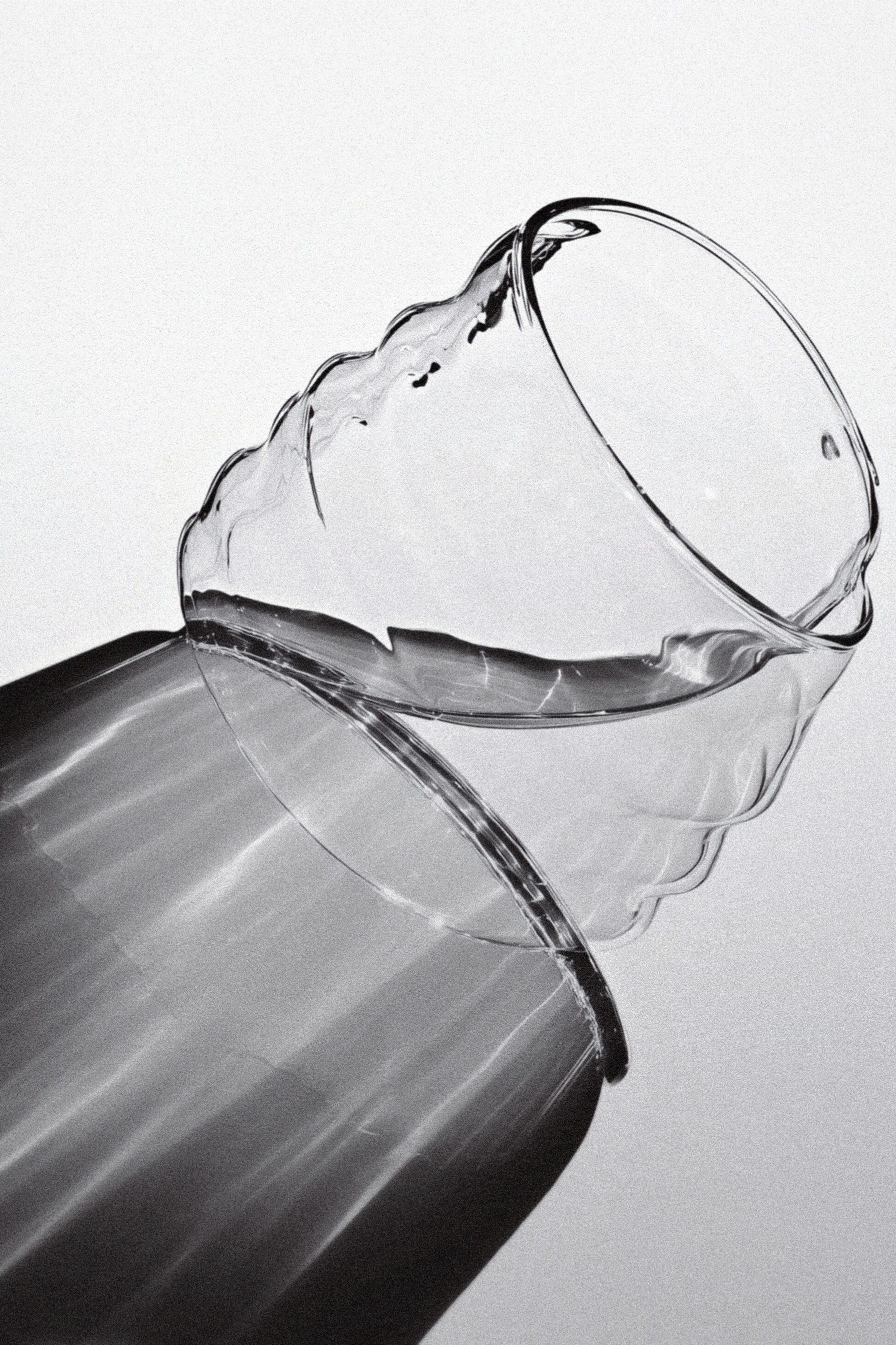 Close-up of a glass tipped over with water spilling across a glossy surface