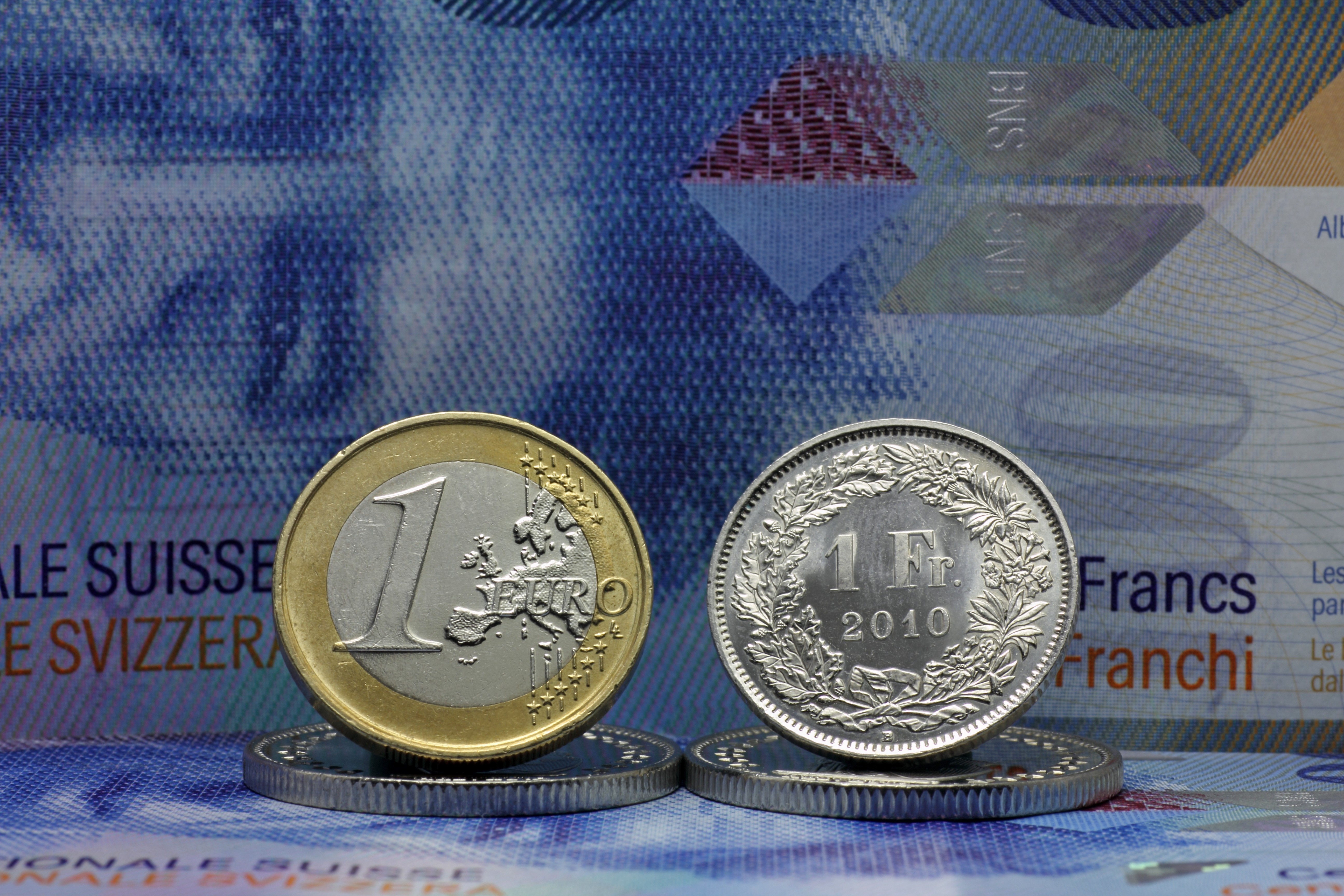 A one Euro coin shown next to a one Swiss franc coin