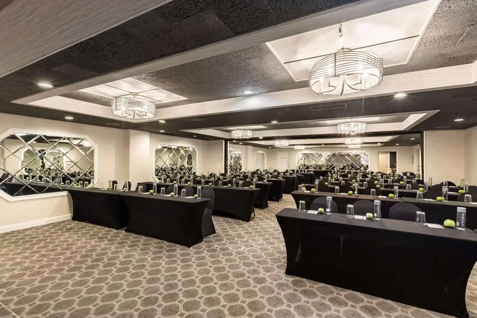 Modern conference room with black tables, chairs, water bottles, and apples.