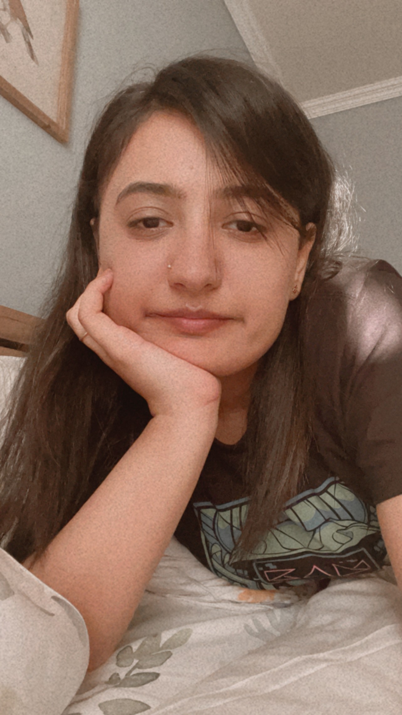 A thoughtful young person with dark hair gazes to the side, captured in soft black and white lighting.