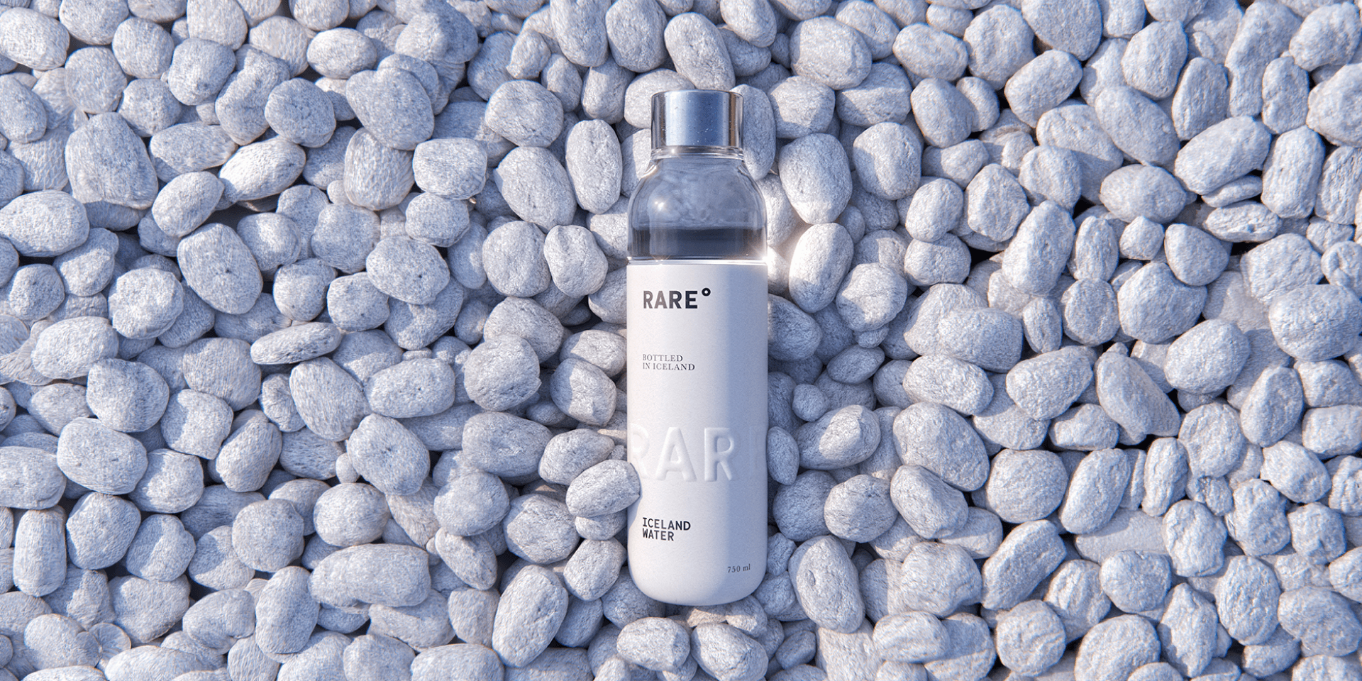 Markenwelt Rare Water – Glasflasche „Iceland Water" auf einem Bett aus weissen Kieselsteinen.