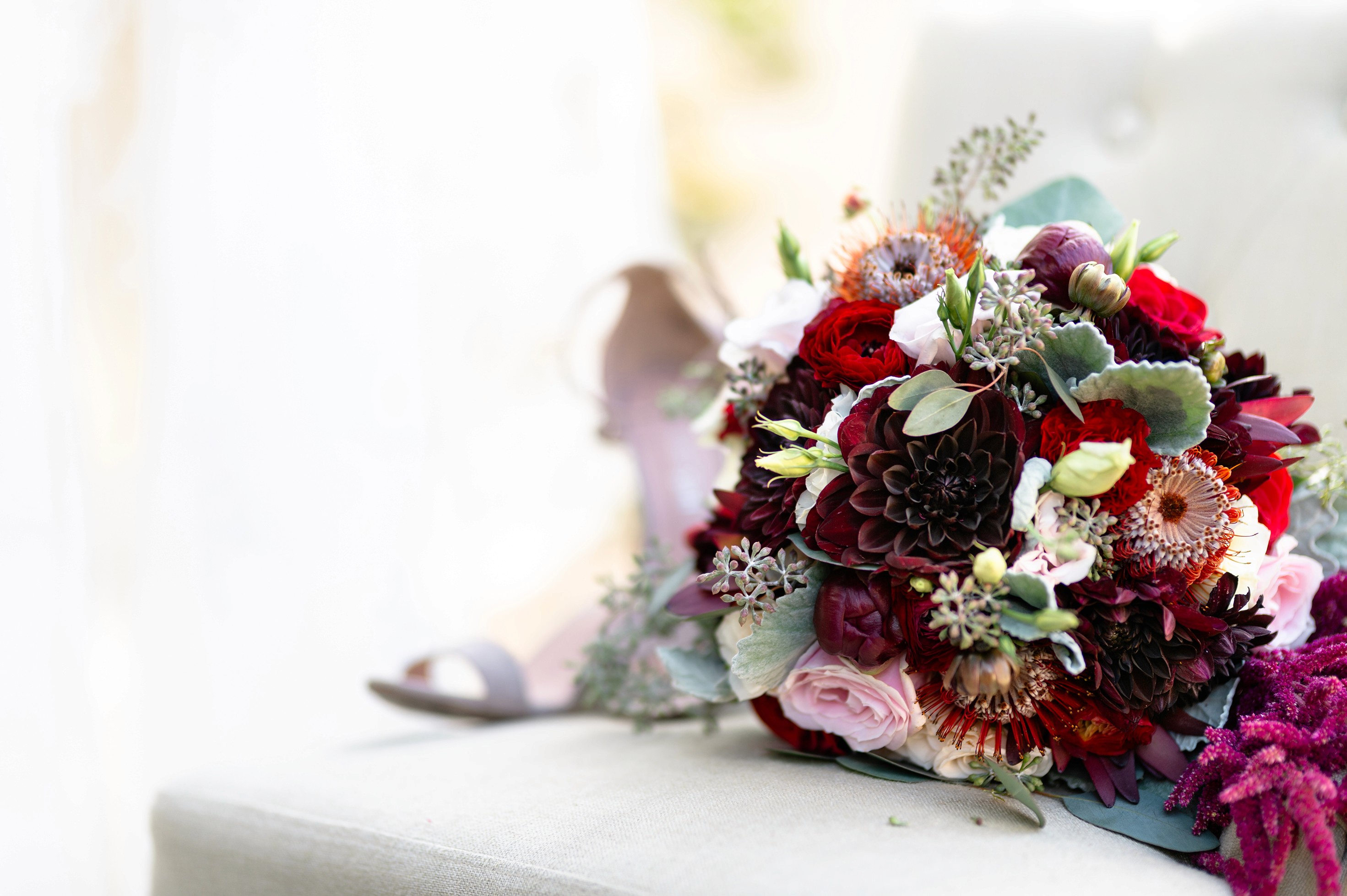 Flat lay wedding details with bouquet, rings, and sparkling bridal heels