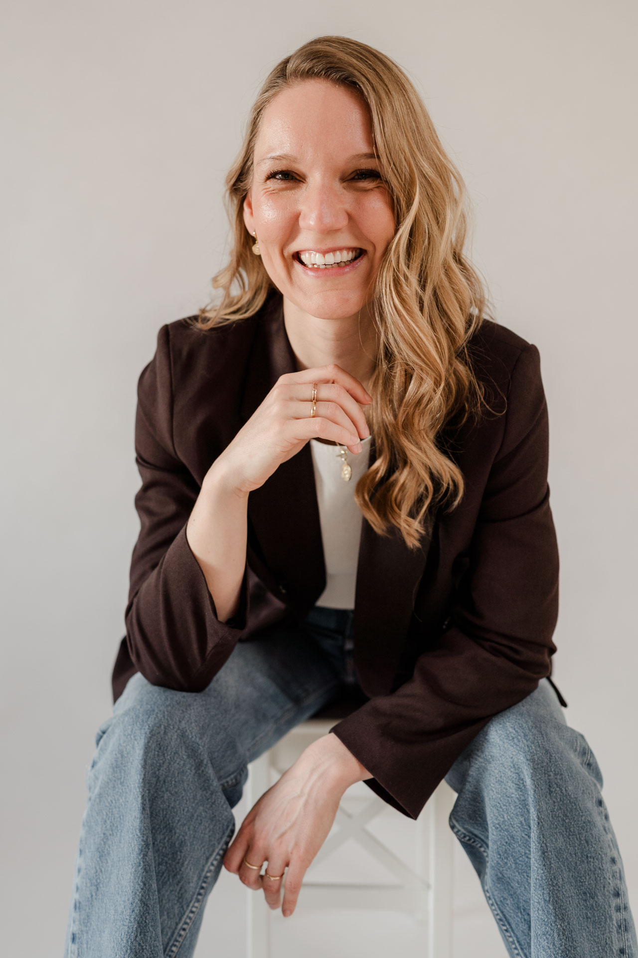 Sitzendes Portrait von OHNORD studio Gründerin Veronika aus Straubing. Sie sitzt auch einem Hocker in entspannter Pose und strahlt eine Ruhe aus, die eine Female Founder braucht. 