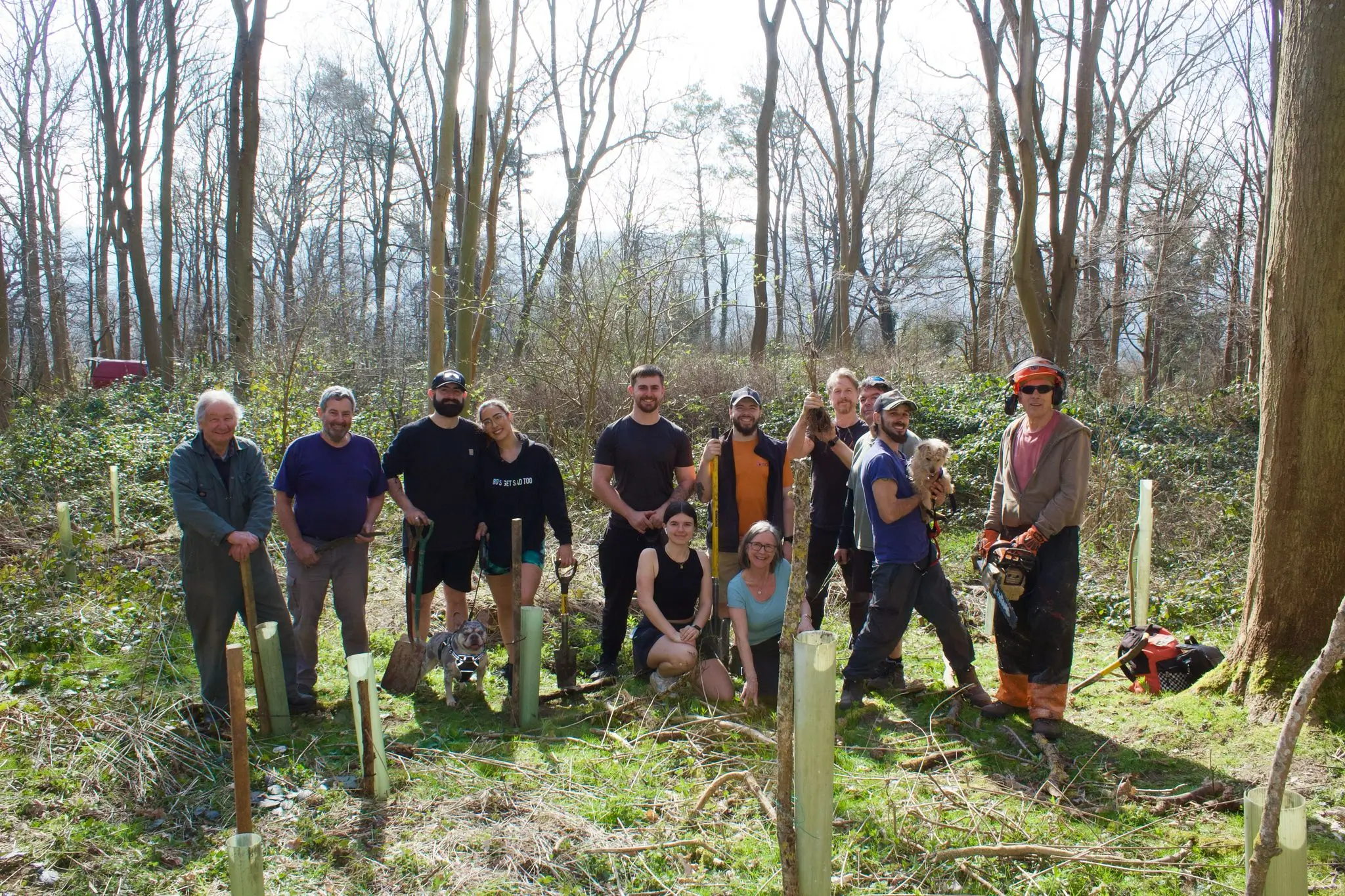 A group of people standing together in a forested area, engaged in outdoor activities.