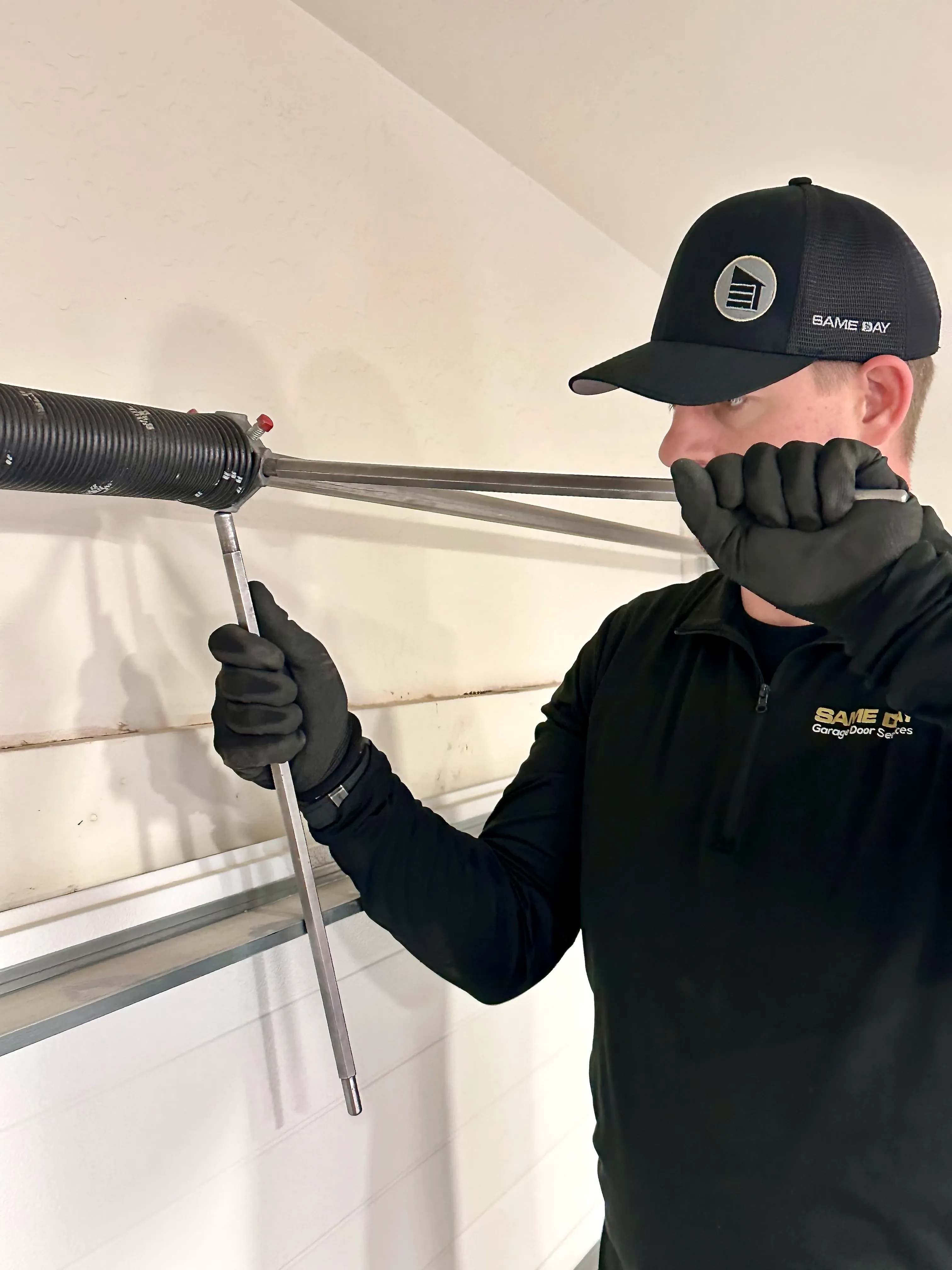 same day garage door services technician tighting a spring on a garage door repair job
