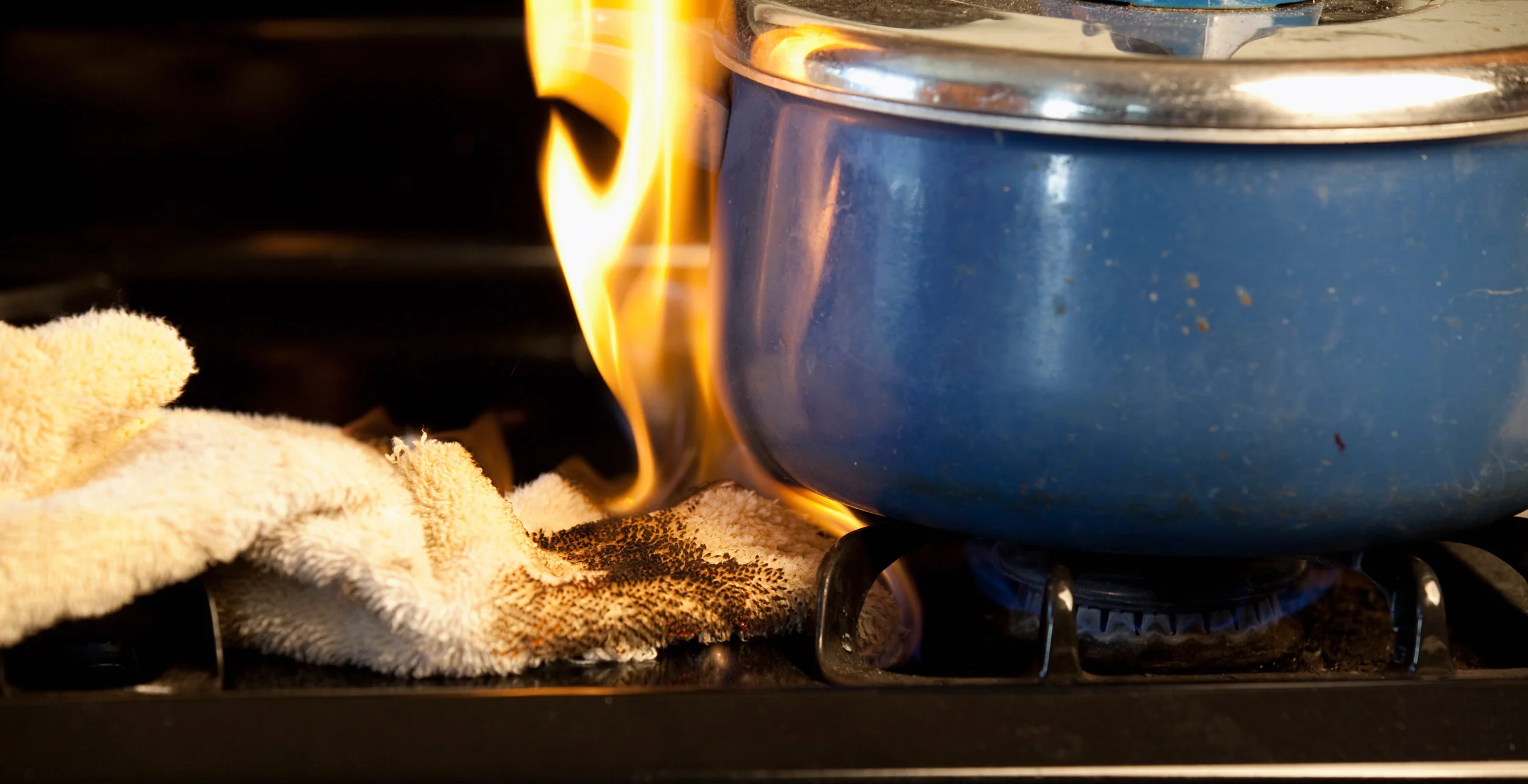 Pot on stove with tea towel on fire