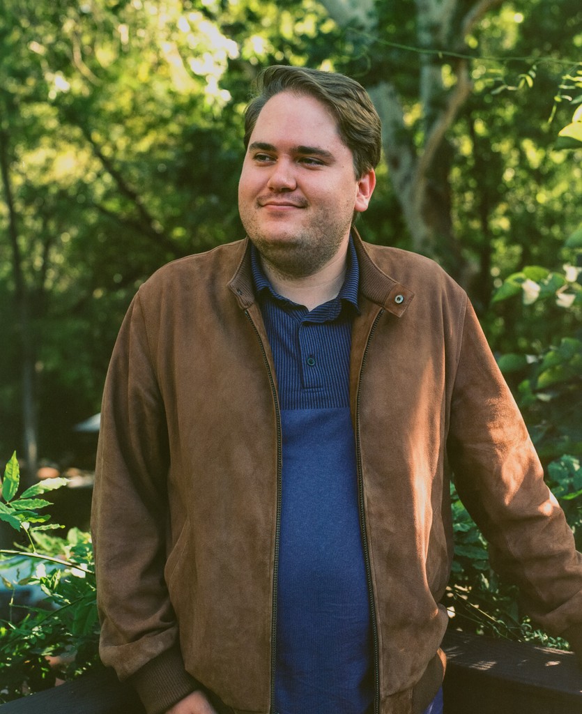 Alex smiling in a brown suede jacket