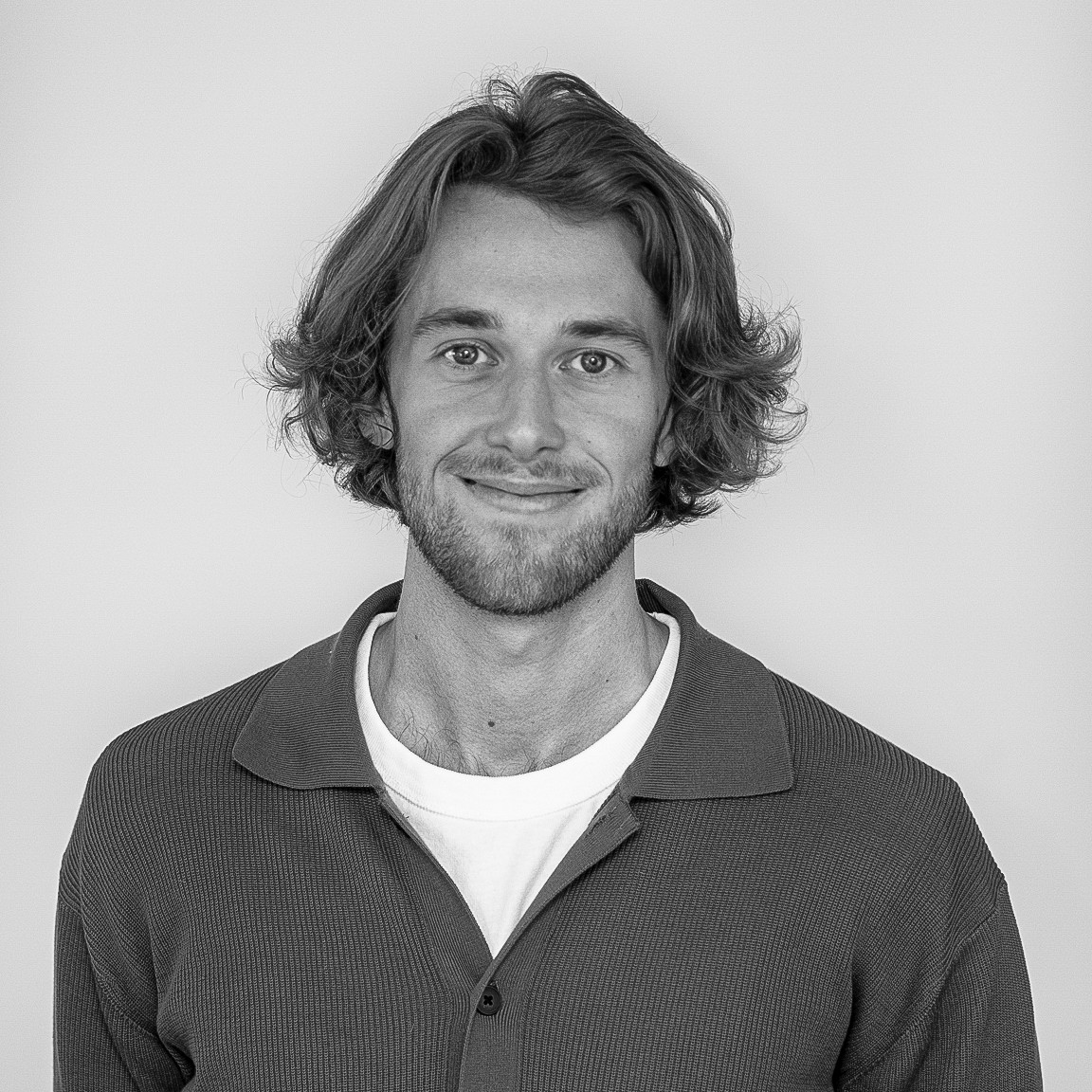 A portait of Lukas, he has a big smile, short beard and long blonde hair.