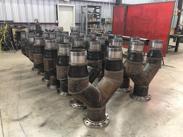 This picture is showing a dozen piping assemblies we fabricated in our fab shop.  These are stainless steel pipe flanges, pipe, and reducers.  These are custom fabricated pipe assemblies using our welding services in a fabrication shop in Henderson, Texas.