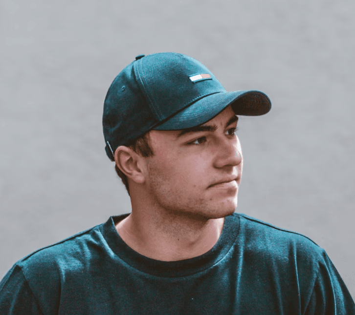a young man wearing glasses standing in front of a mountain
