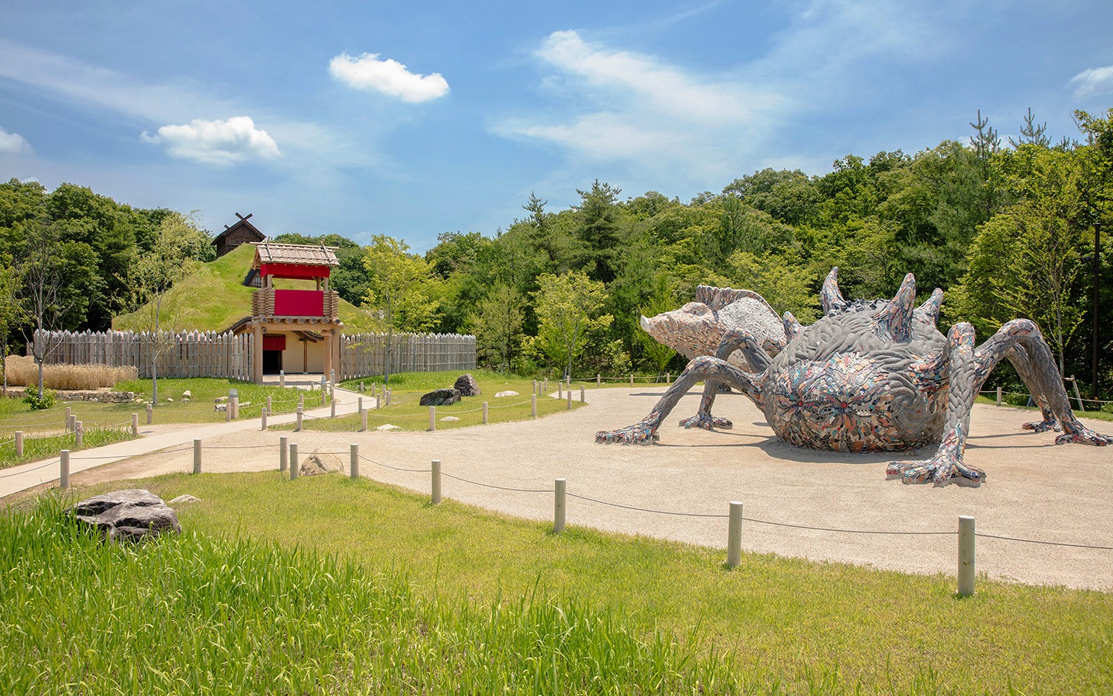 Giant creature sculpture at Ghibli Park's Mononoke Village, surrounded by greenery and traditional architecture.