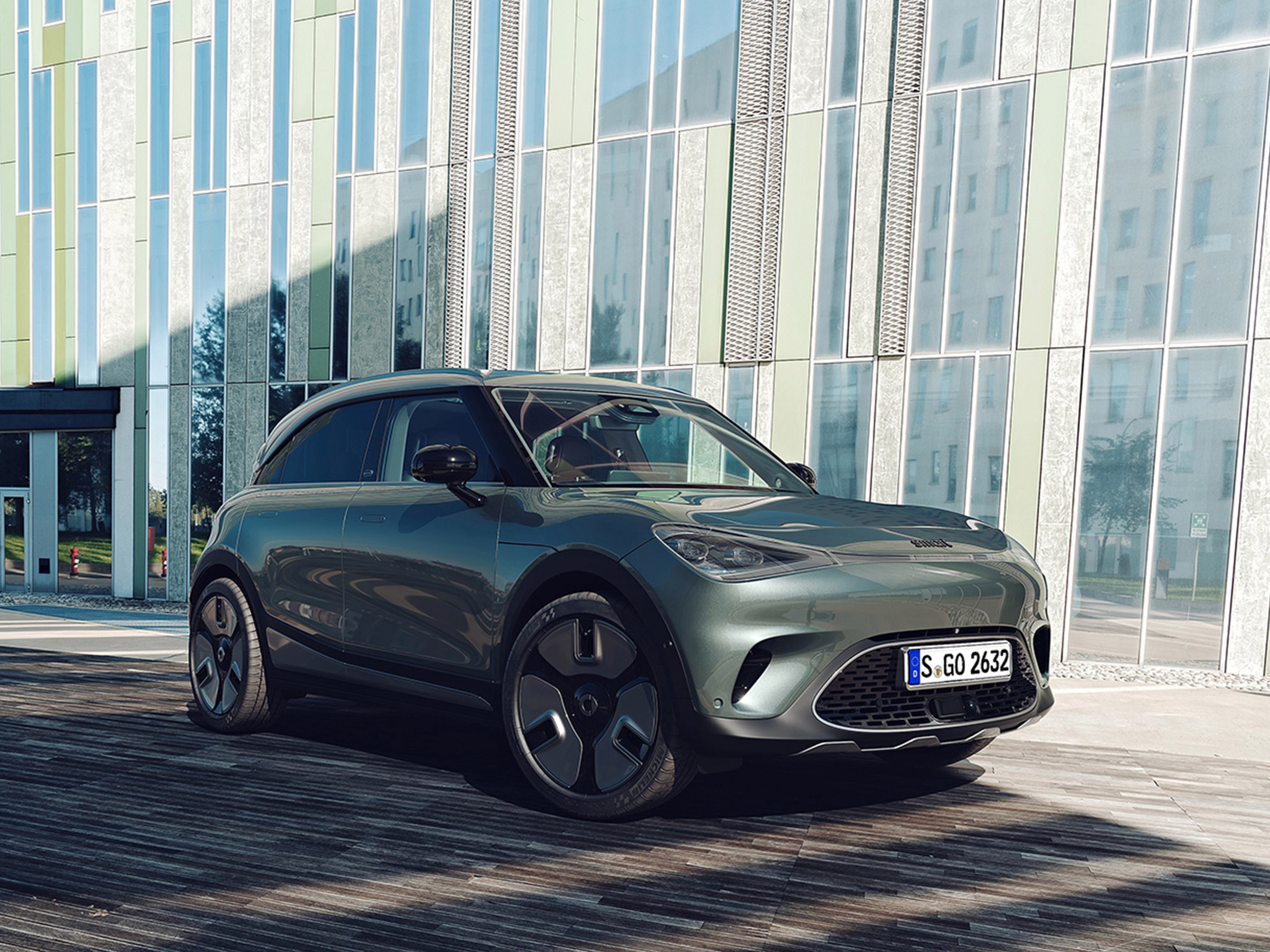 Render 3d automotive di Smart 3 con carrozzeria metallizzata verde con vetrate di uffici come sfondo.