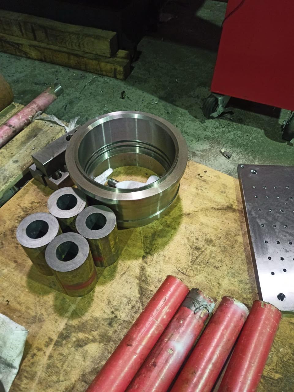 Stacked industrial metal rings placed on a workbench next to technical engineering design drawings.