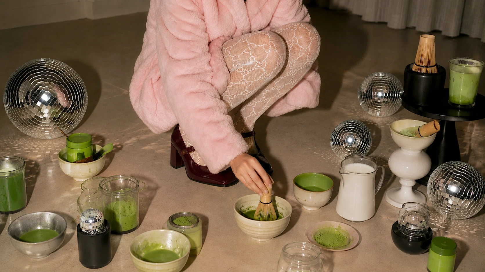 A bamboo matcha whisk resting beside a bowl of matcha