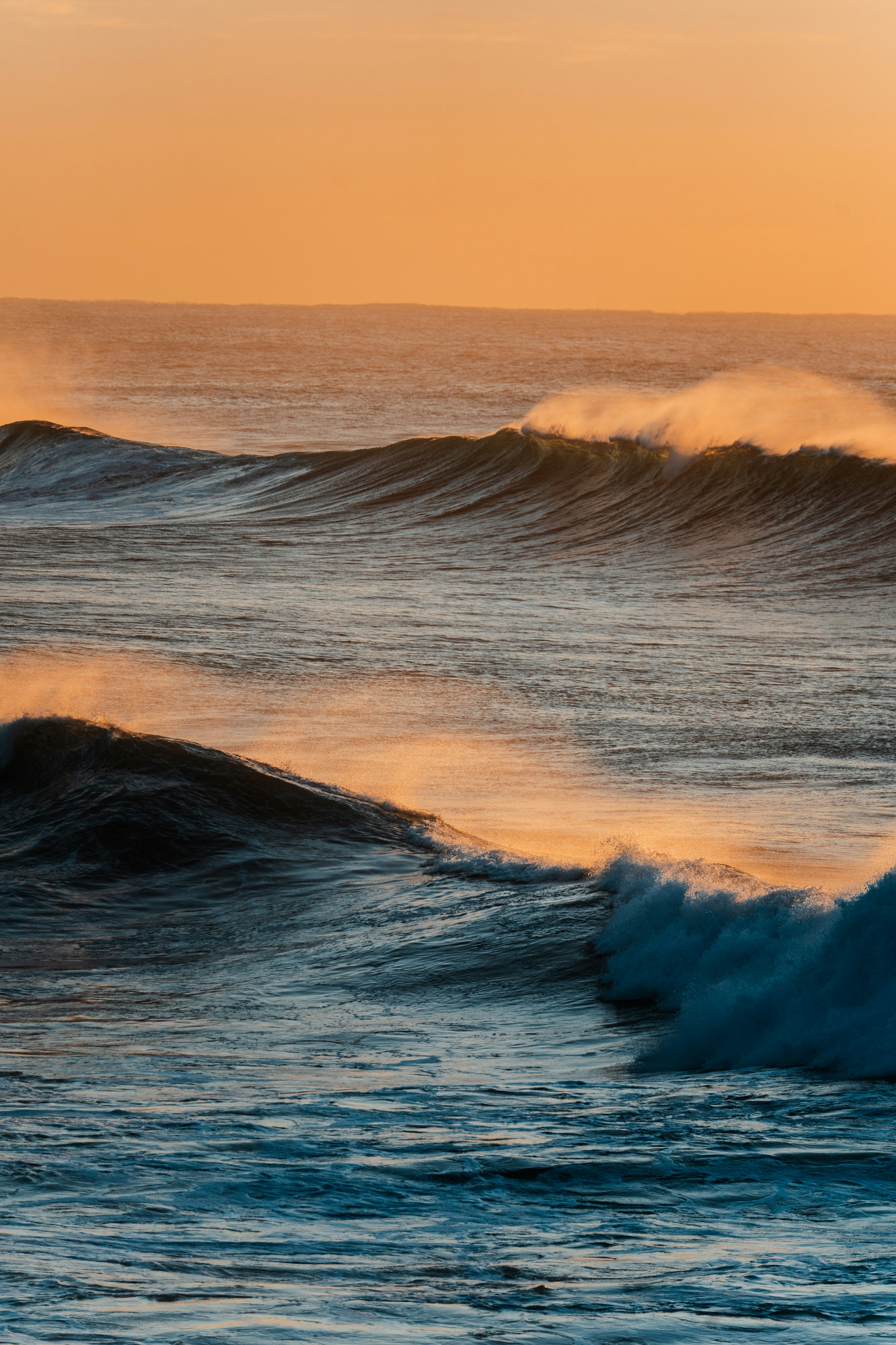 Ocean waves at sunset with warm orange sky
