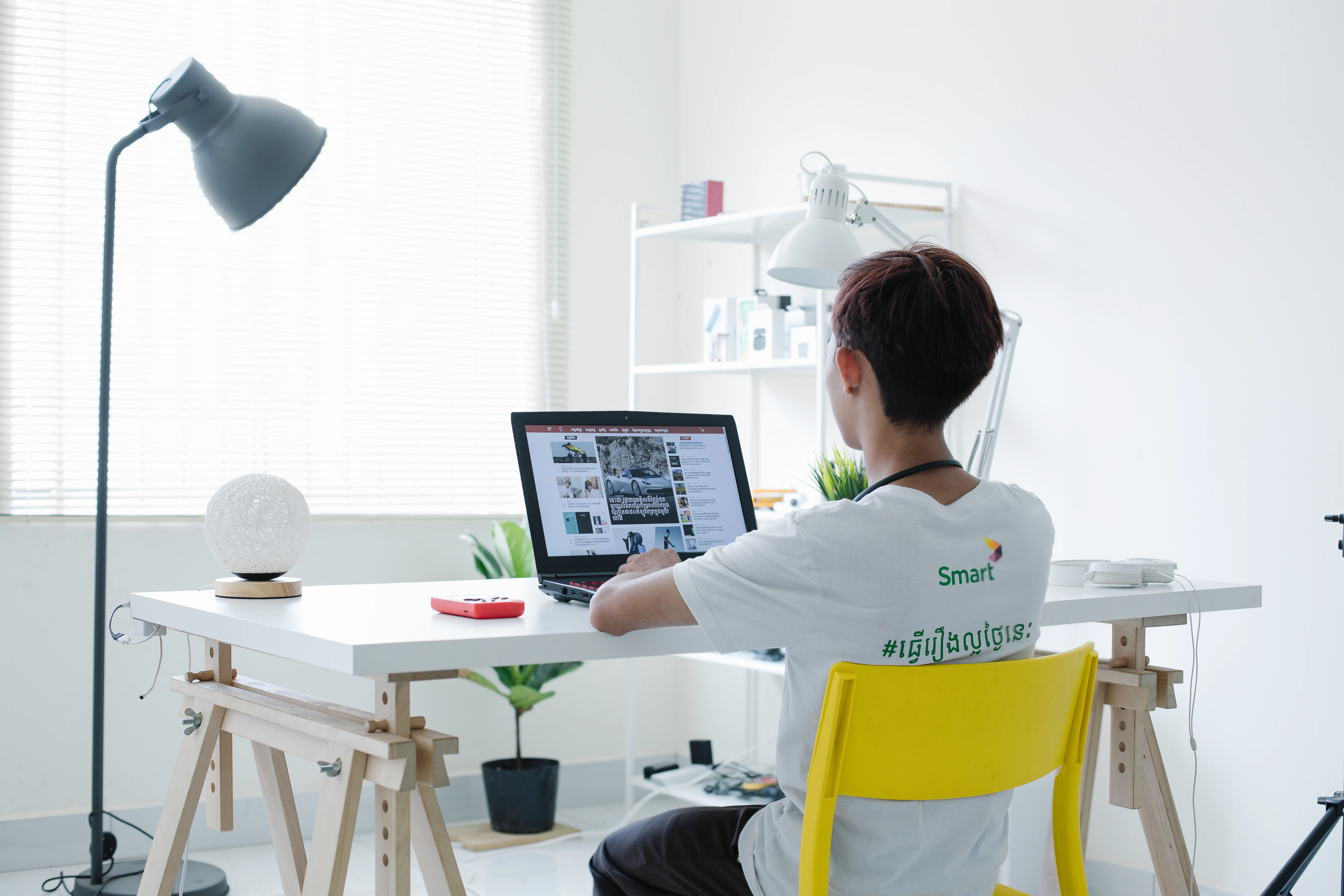 Person working at a minimalist white desk with a laptop in a bright, modern home office