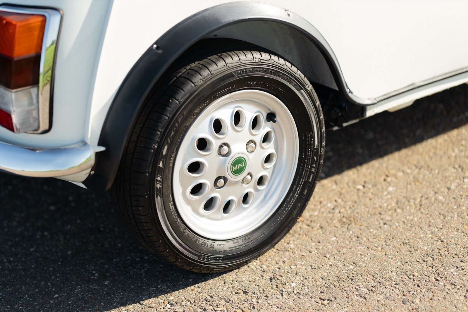 Close-up of a tire with white alloy rims on a vehicle, showing details of the wheel design and tread.