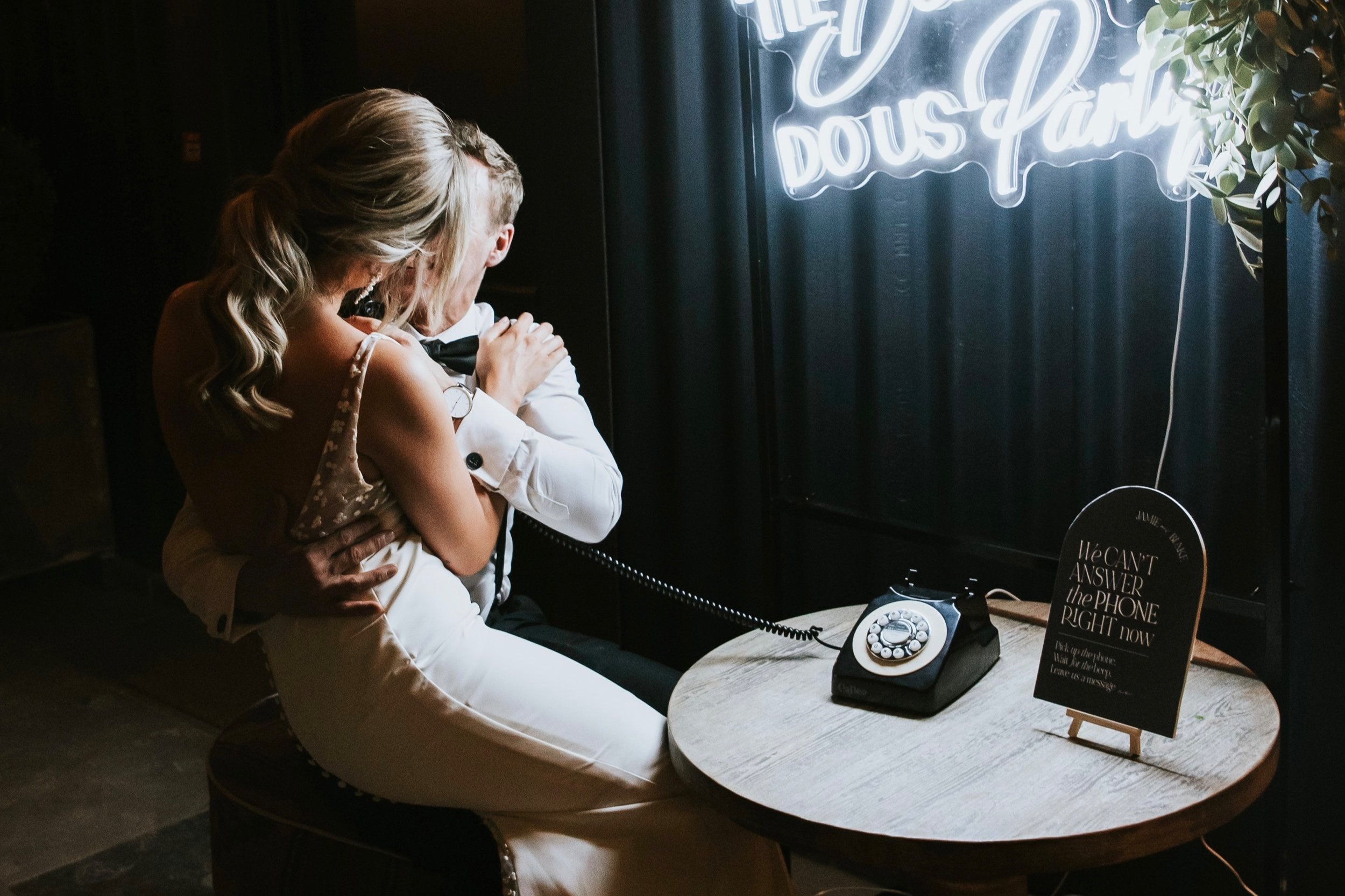 A bride smiles warmly as she listens to messages on a vintage phone from her audio guestbook at the wedding reception
