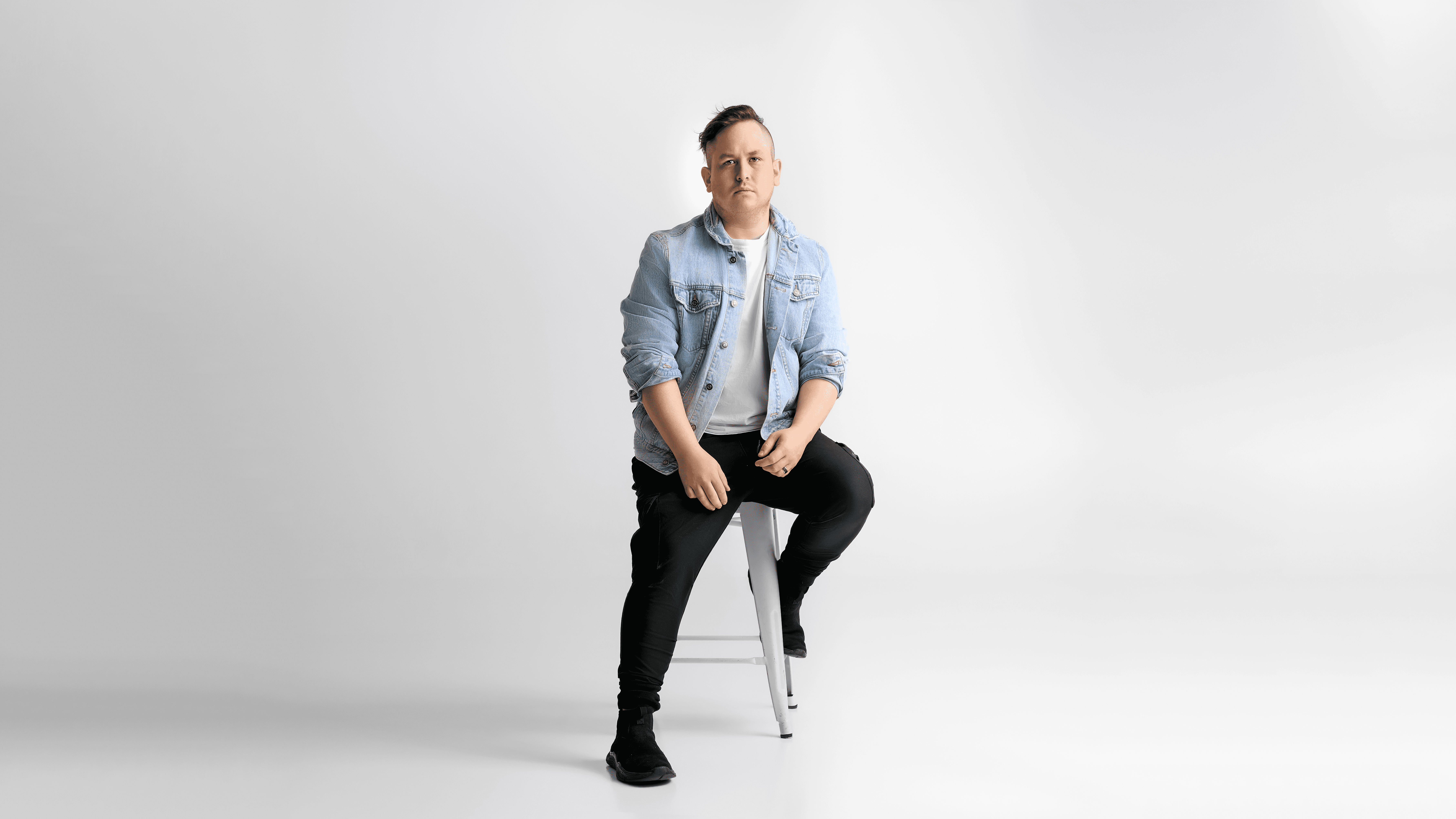 Black and white image of people working at a table with laptops, showing hands gesturing during discussion of digital content displayed on screens, with fabrica® logo in the corner.