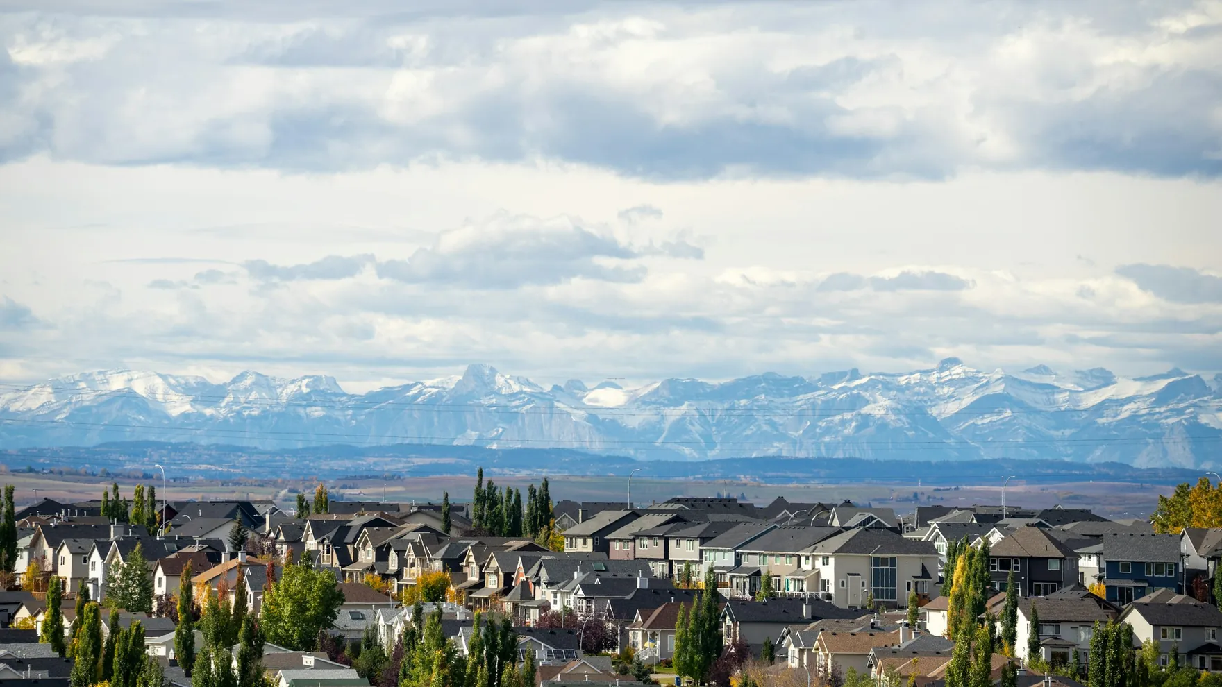 Rooftops of a residential neighbourhood with the snow-capped Rocky Mountains behind